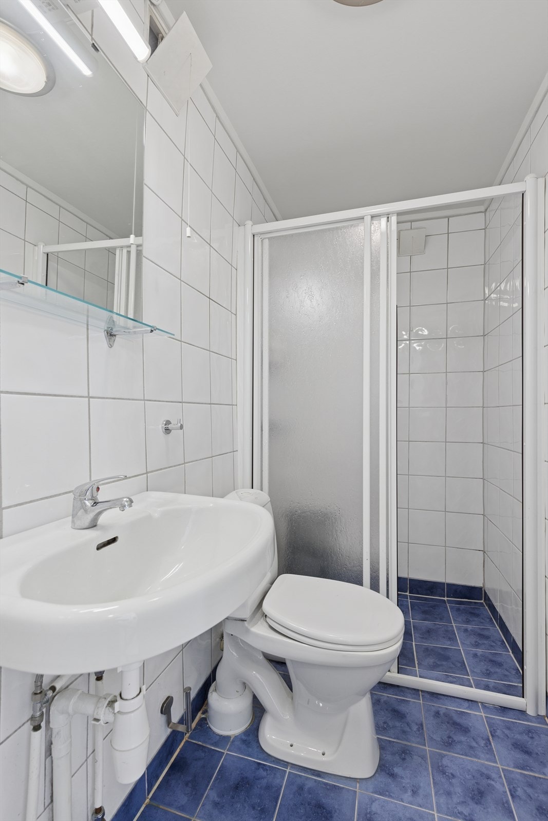 Badet i sokkeletasjen har fliset på gulv og vegger. Dusjnisje, vask og toalett. Galleribilde