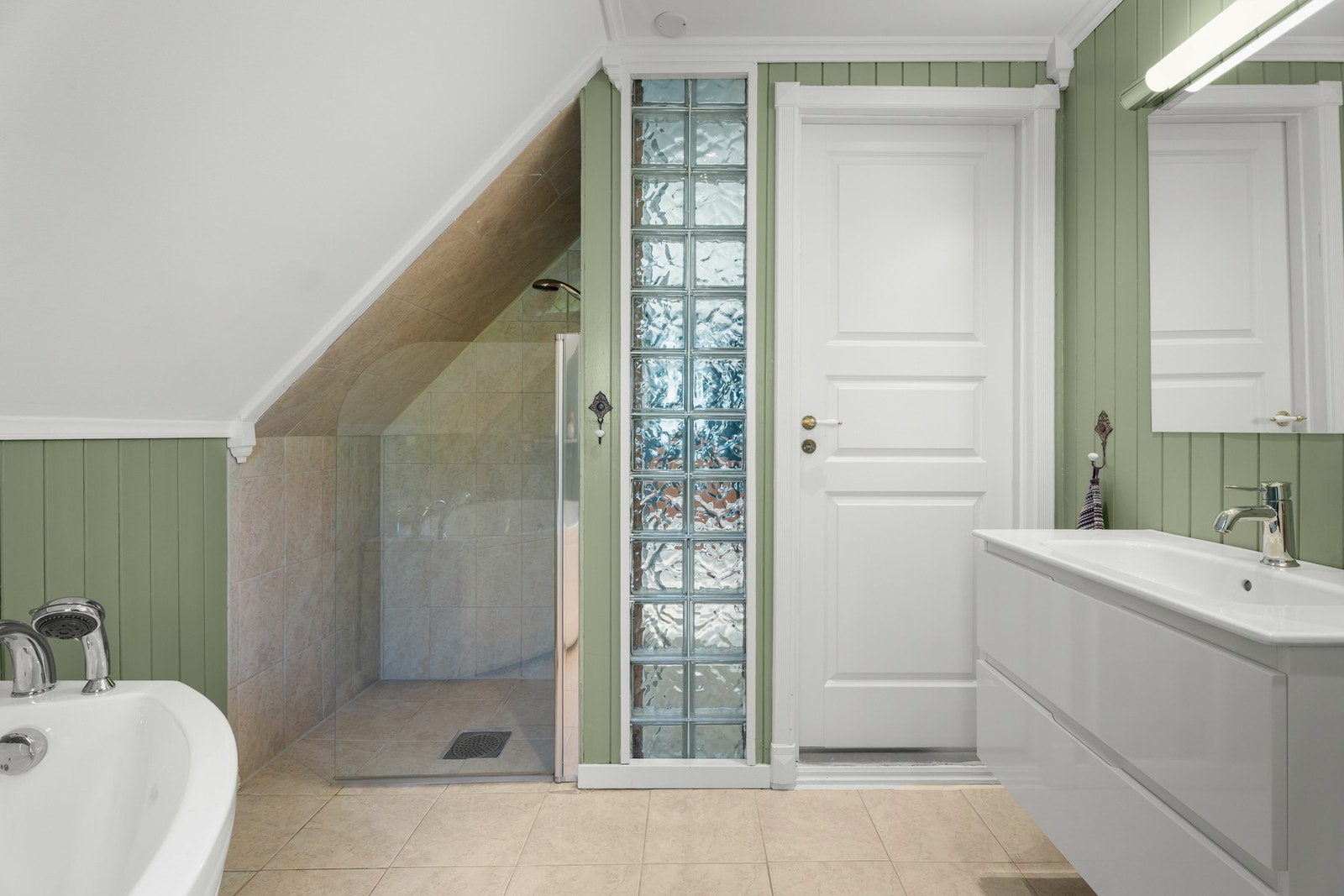 Badet i andre etasje har grønnmalt panel på veggene og beige fliser på gulv med elektrisk gulvvarme. Galleribilde