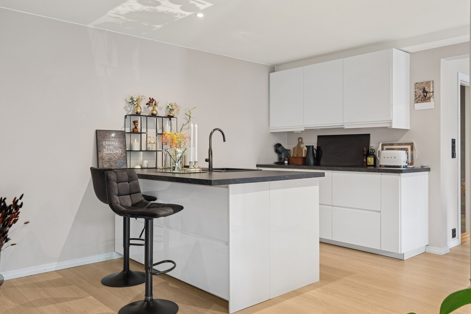 Moderne og stilrent kjøkken fra 2020 i en åpen stue- kjøkken løsning med hvite, høyglans fronter og laminert benkeplate som gir et rent og tidløst uttrykk. Galleribilde