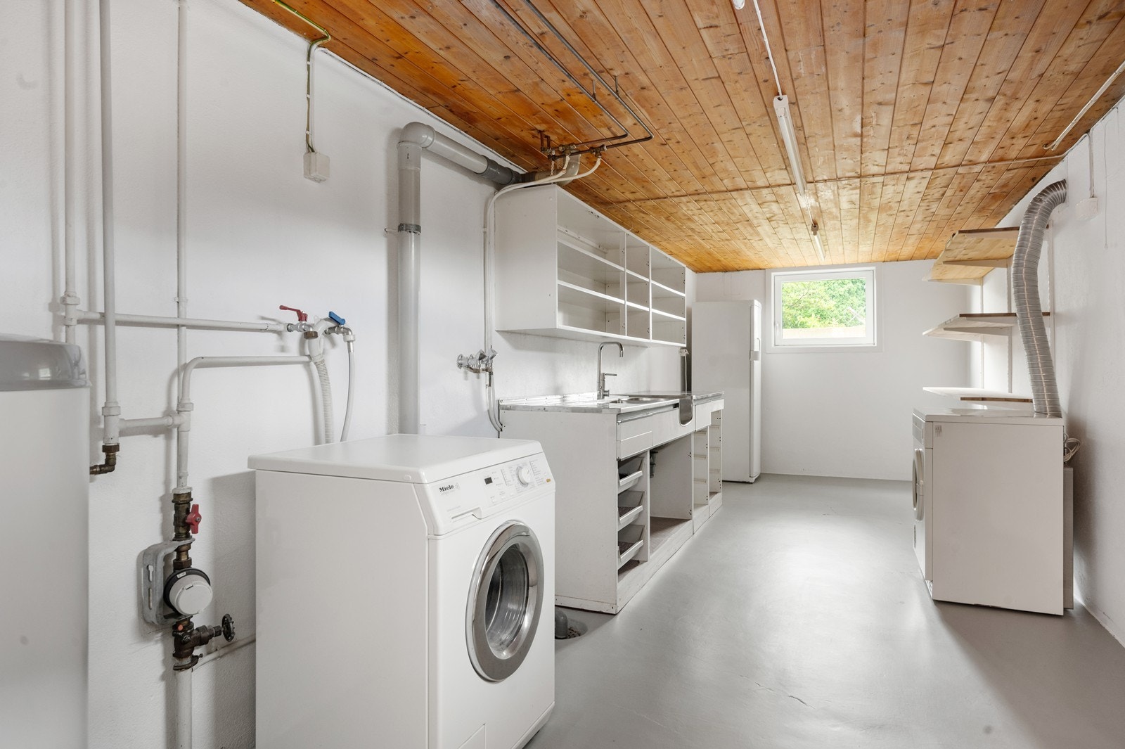 Et stort og funksjonelt vaskerom med opplegg for vaskemaskin og tørketrommel. Galleribilde