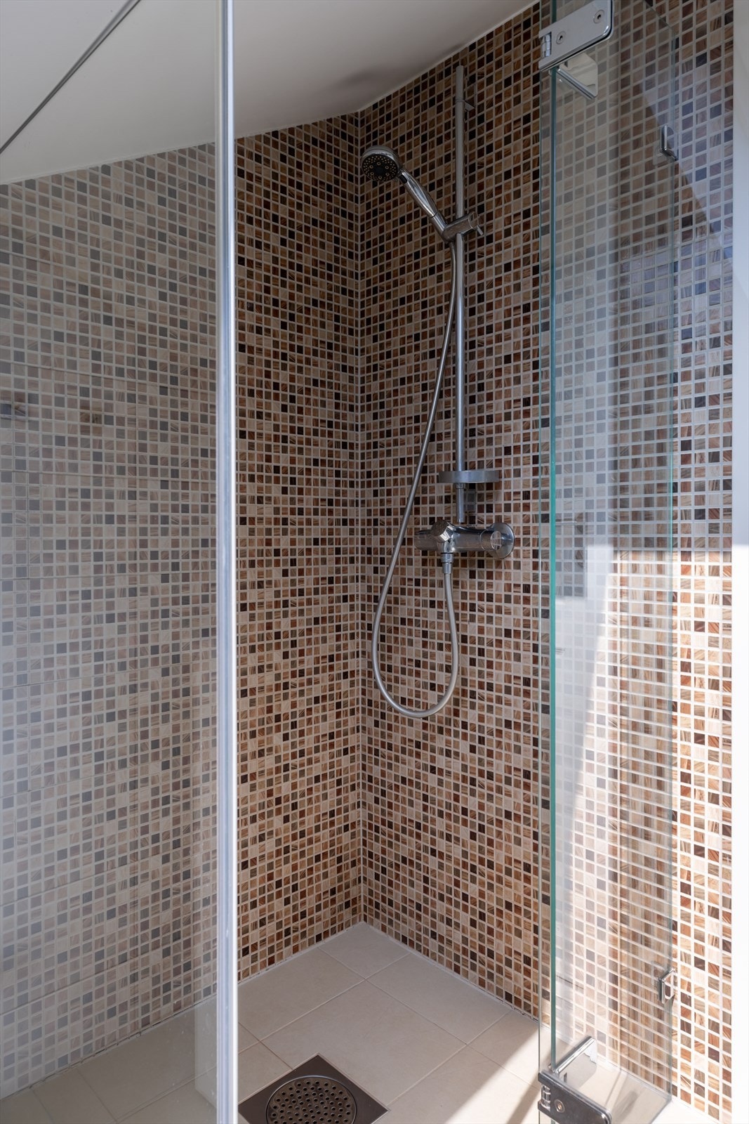Romslig dusjhjørne med moderne fliser og innfellbar glassvegg. Galleribilde