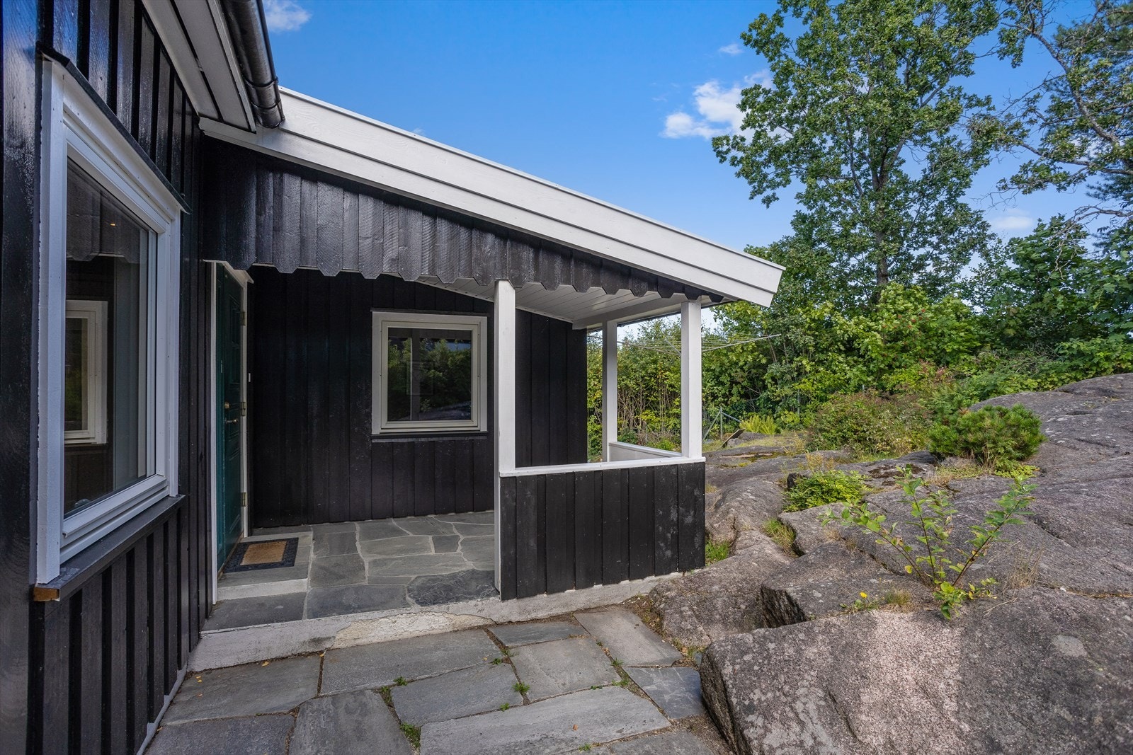 Ved inngangsparti, både ved overbygg og langs østvegg er det en platting i bruddskifer. Galleribilde