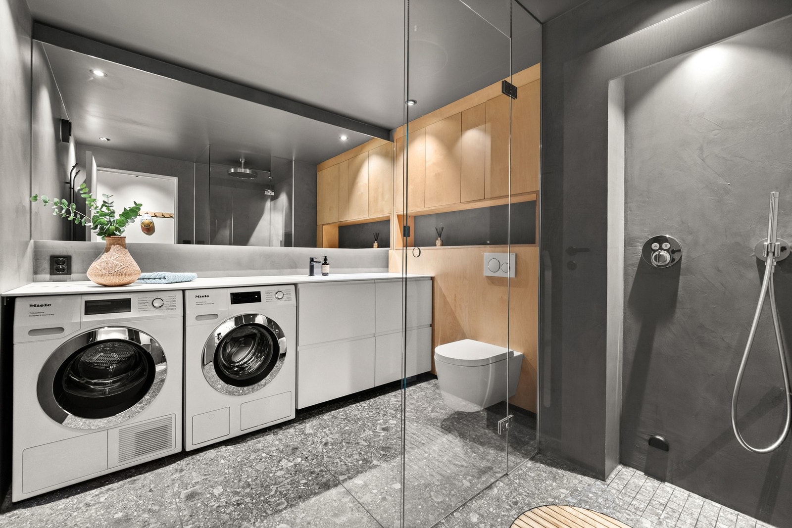 Stort, praktisk flislagt baderom med opplegg for vaskemaskin og tørketrommel. Galleribilde
