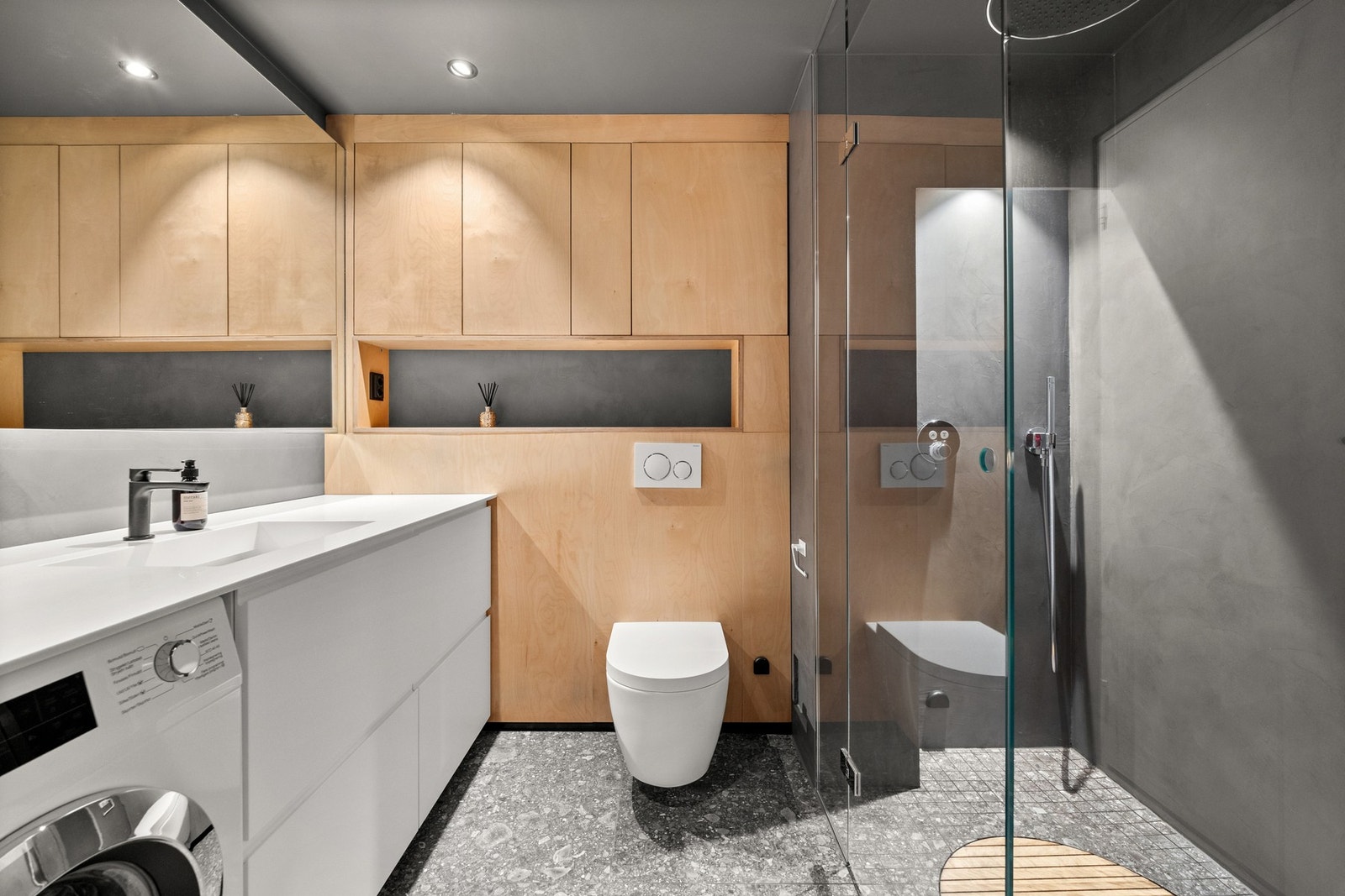 Moderne bad med kvalitetsmaterialer og tidløs design: Corian-servant, mikrosementvegger, flislagt gulv med gulvvarme, skjult LED-belysning og ekstra stort dusjhode Galleribilde