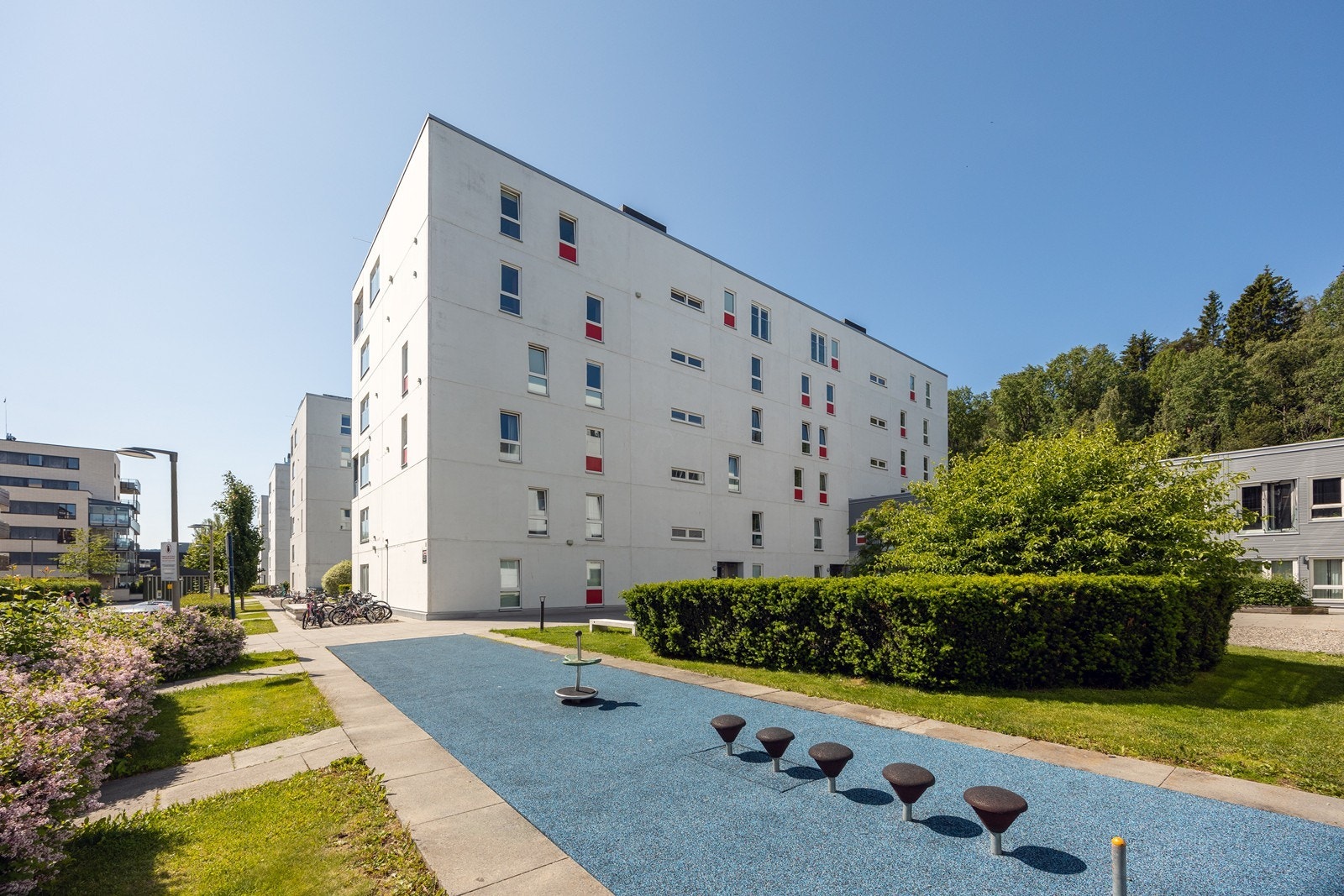 Utenfor leilighetsbygget er det pent opparbeidet med grønn plen, beplantning og steinheller. I tillegg er det sykkelparkering og lekeareal. Galleribilde