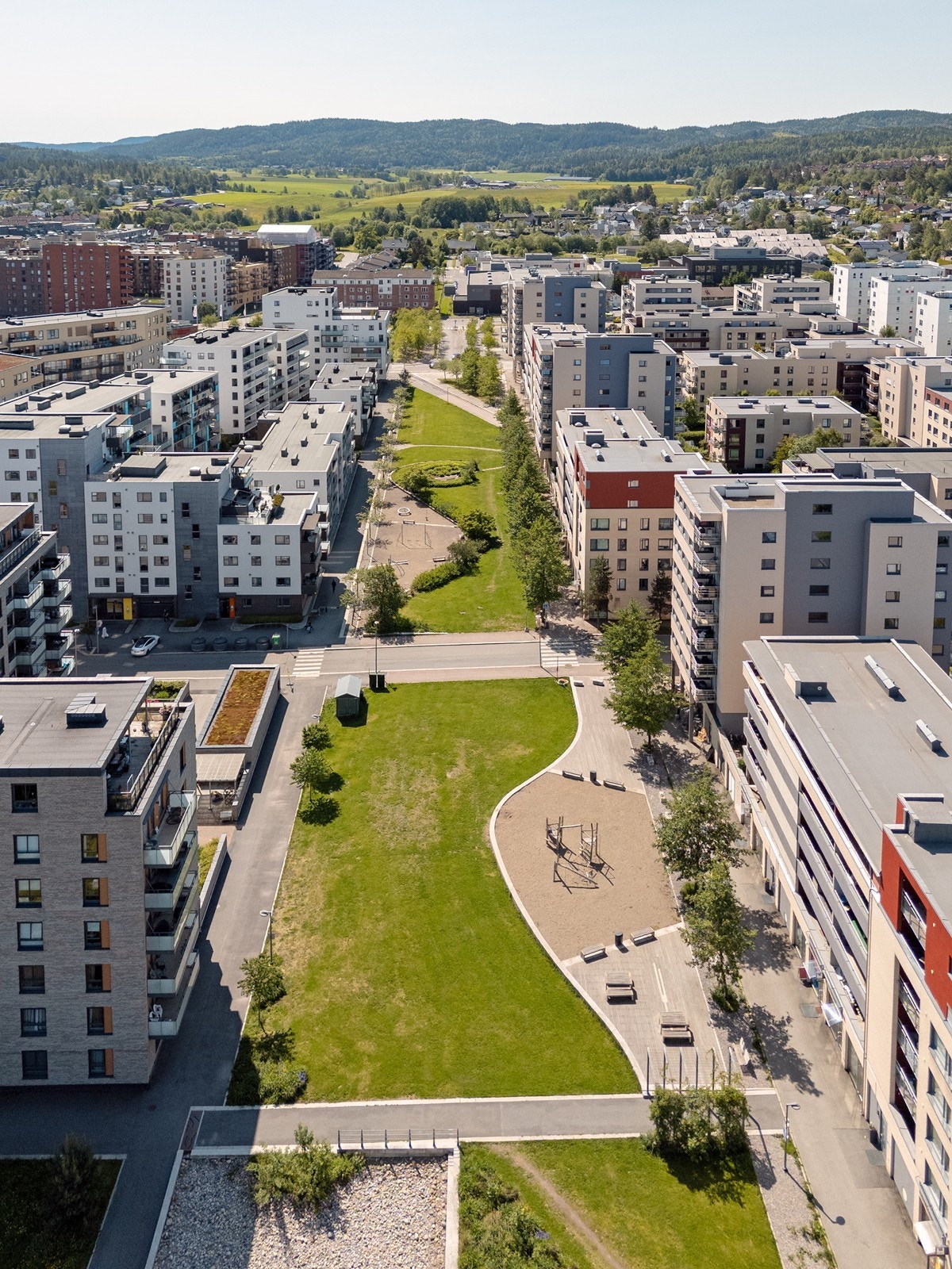 Mellom leilighetsbyggene er det pent opparbeidede områder med plen, lekeplasser og sittebenker. Galleribilde