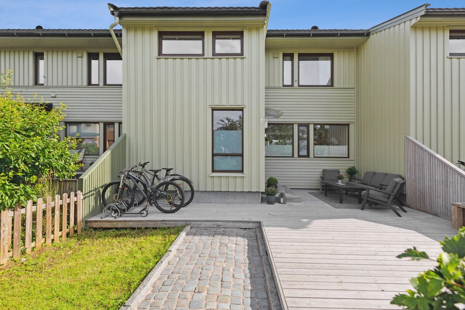 Velholdt og praktisk inngangsparti med solrik terasse, plass for sykkelpaerkering, sittegrupper, grill m.m. Galleribilde