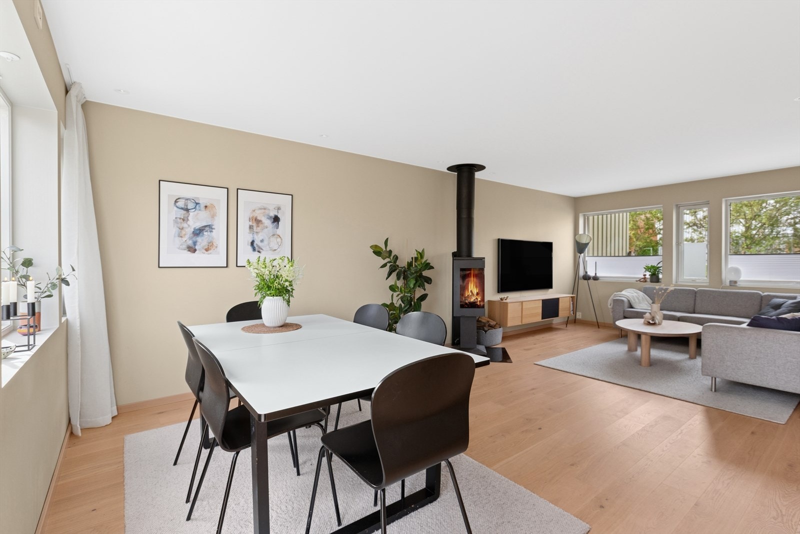 En lys og romslig stue med peisovn sentralt plassert mellom spisestuen og sofagruppen. Ny pipe i 2022. Galleribilde