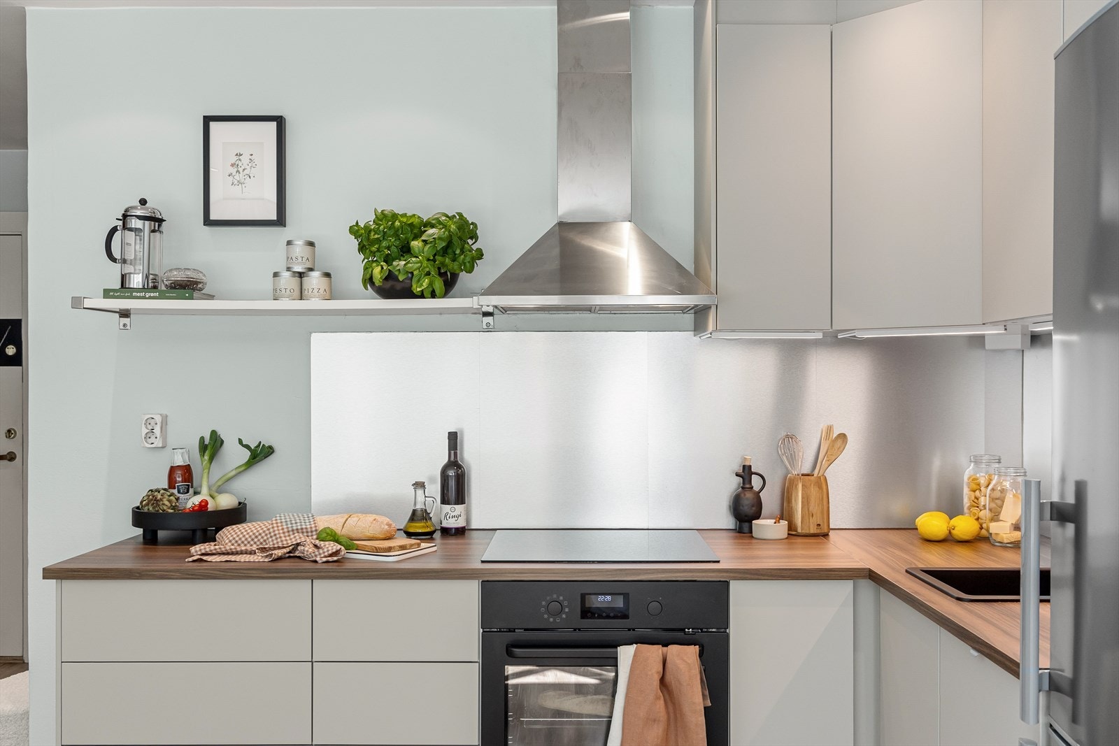 Nyere, moderne kjøkken fra Ikea med glatte fronter, laminatplater på vegg over kjøkkenbenk og benkeplate i laminat. Galleribilde