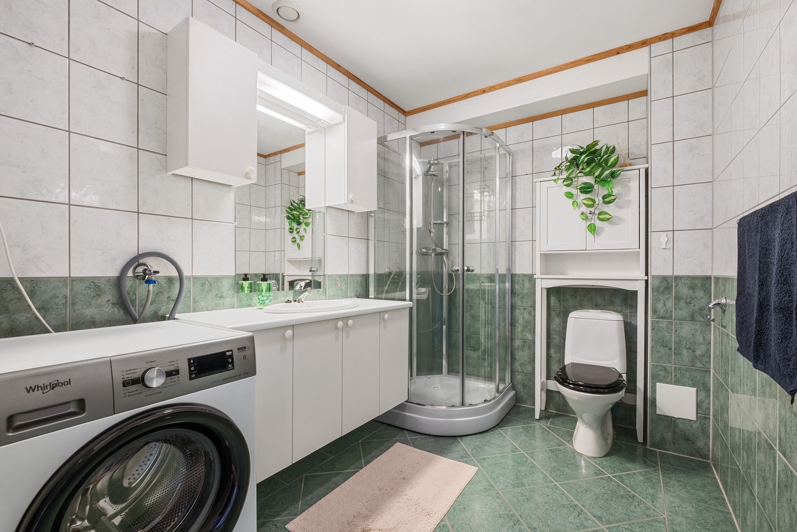Det flislagte badet er utstyrt med toalett, servant, baderomsinnredning, dusjkabinett og opplegg for vaskemaskin. Galleribilde