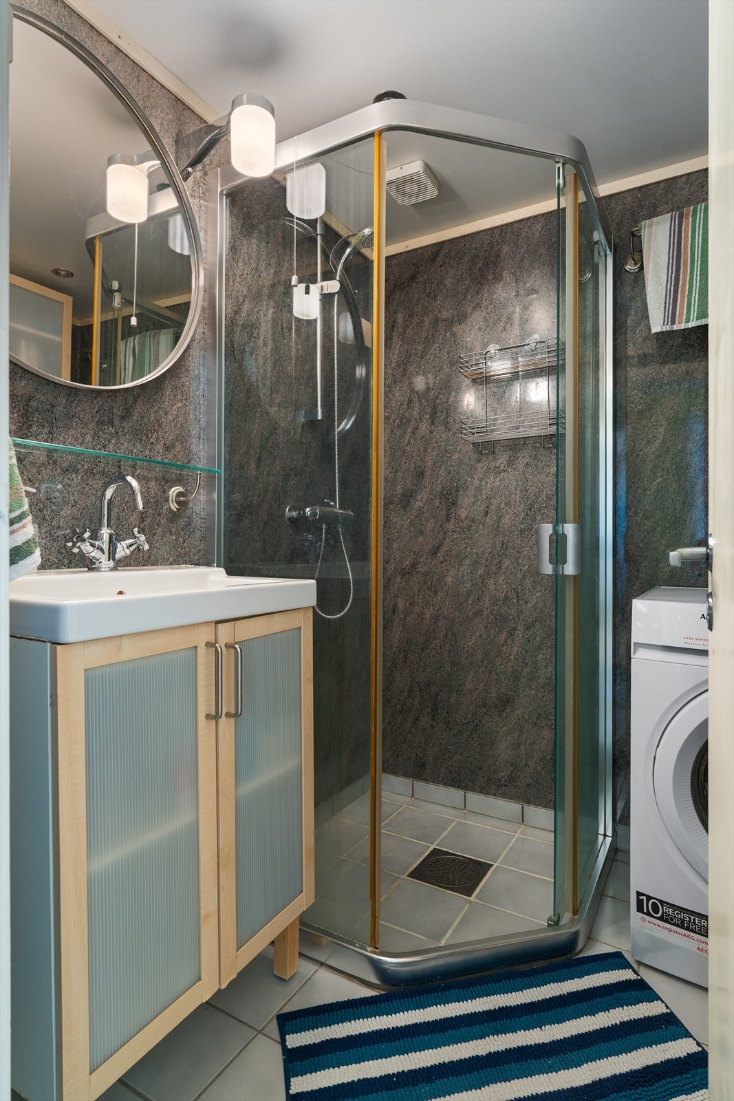 Badet har et flislagt gulv, våtromsplater på vegg og malt slett himling. Opplegg for både vaskemaskin og tørketrommel. Galleribilde