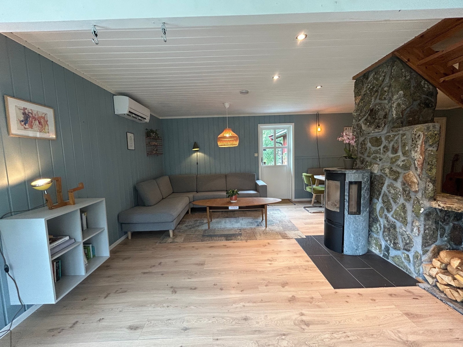 Stue med peisovn fra 2016 og natursteinbelagt pipe. Vegger er malt i en behagelig blåtone. Varmepumpe installert i 2023. Galleribilde