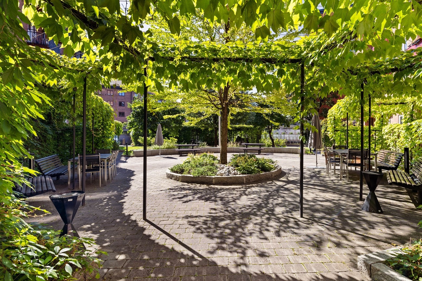 Innbydende uteområde med frodig beplantning og flere hyggelige sitteplasser. Galleribilde