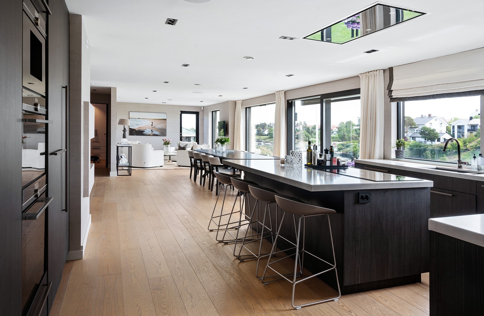 Åpen stue/kjøkkenløsning med snekkerbygd kjøkkeninnredning fra Oslo kjøkkenstudio. Galleribilde