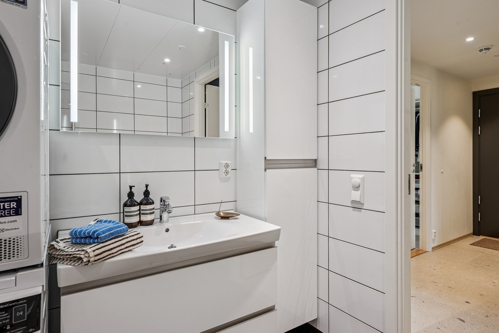 Innredningen består av servantseksjon med slette fronter, speil med belysning, vegghengt toalett og dusjhjørne med innfellbare glassdører Galleribilde