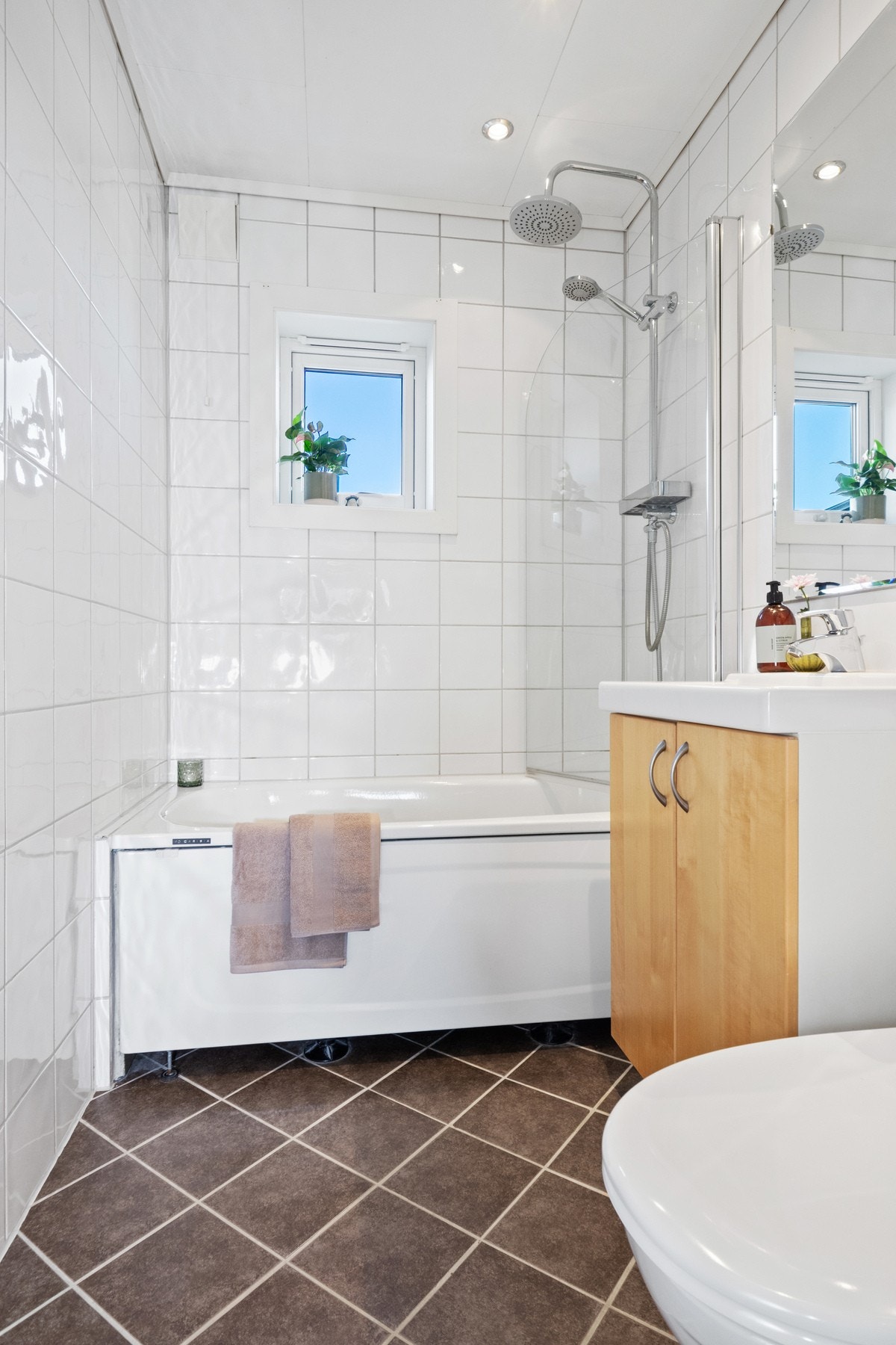 Badet er innredet med hvite veggfliser og mørke gulvfliser for en fin kontrast. Galleribilde