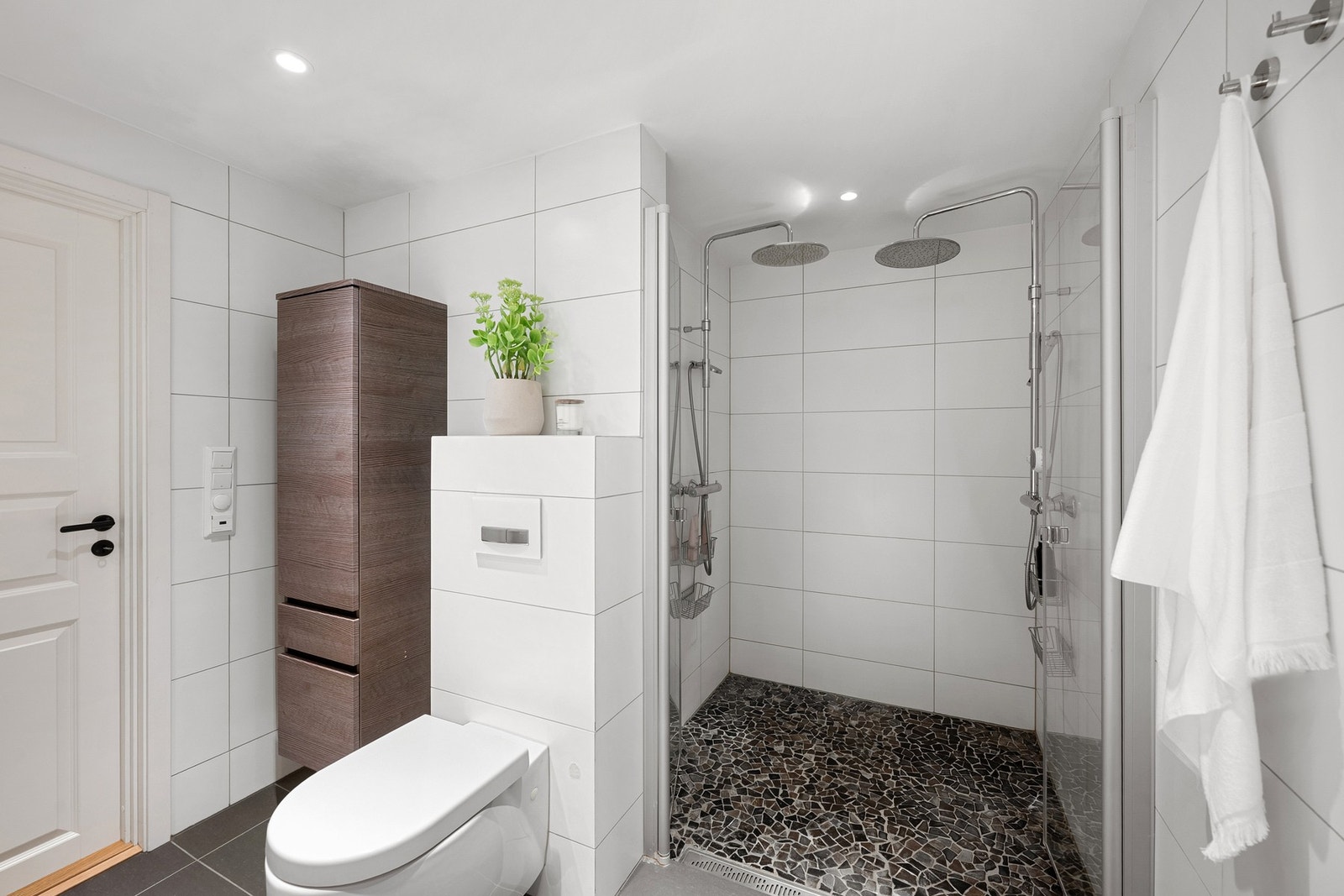Badet har både dusjnisje med doble armaturer og innfellbare glassdører, samt et romslig hjørnebadekar. Galleribilde