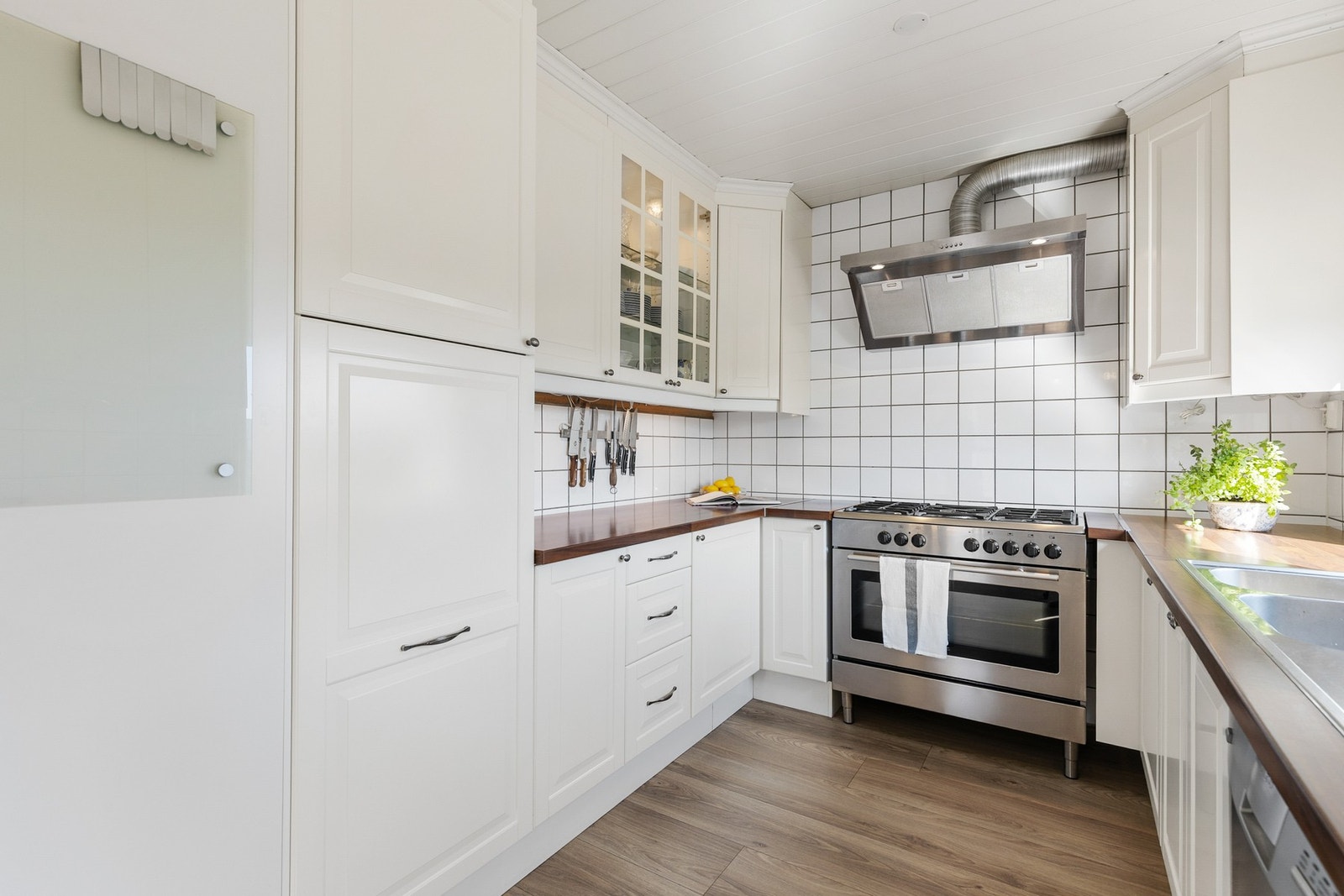 Kjøkkenet har frittstående hvitevarer, herunder kjøleskap, oppvaskmaskin og gasskomfyr Galleribilde