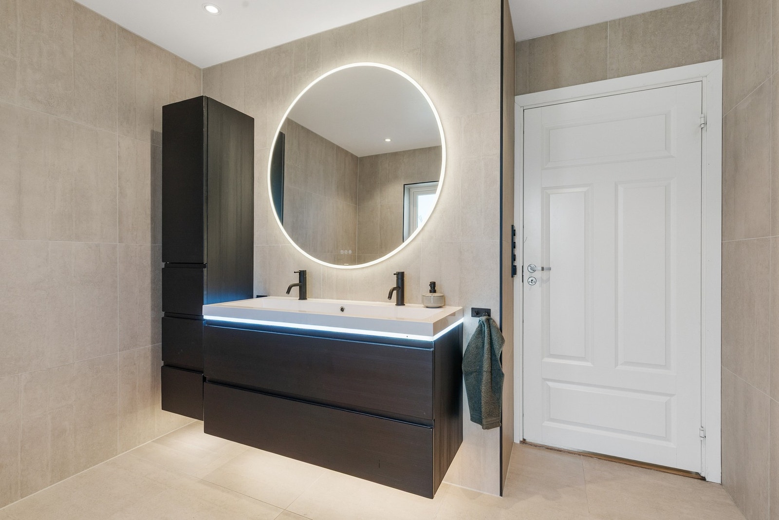 Badet har en pen baderomsinnredning med nedsunket servant og speil Galleribilde