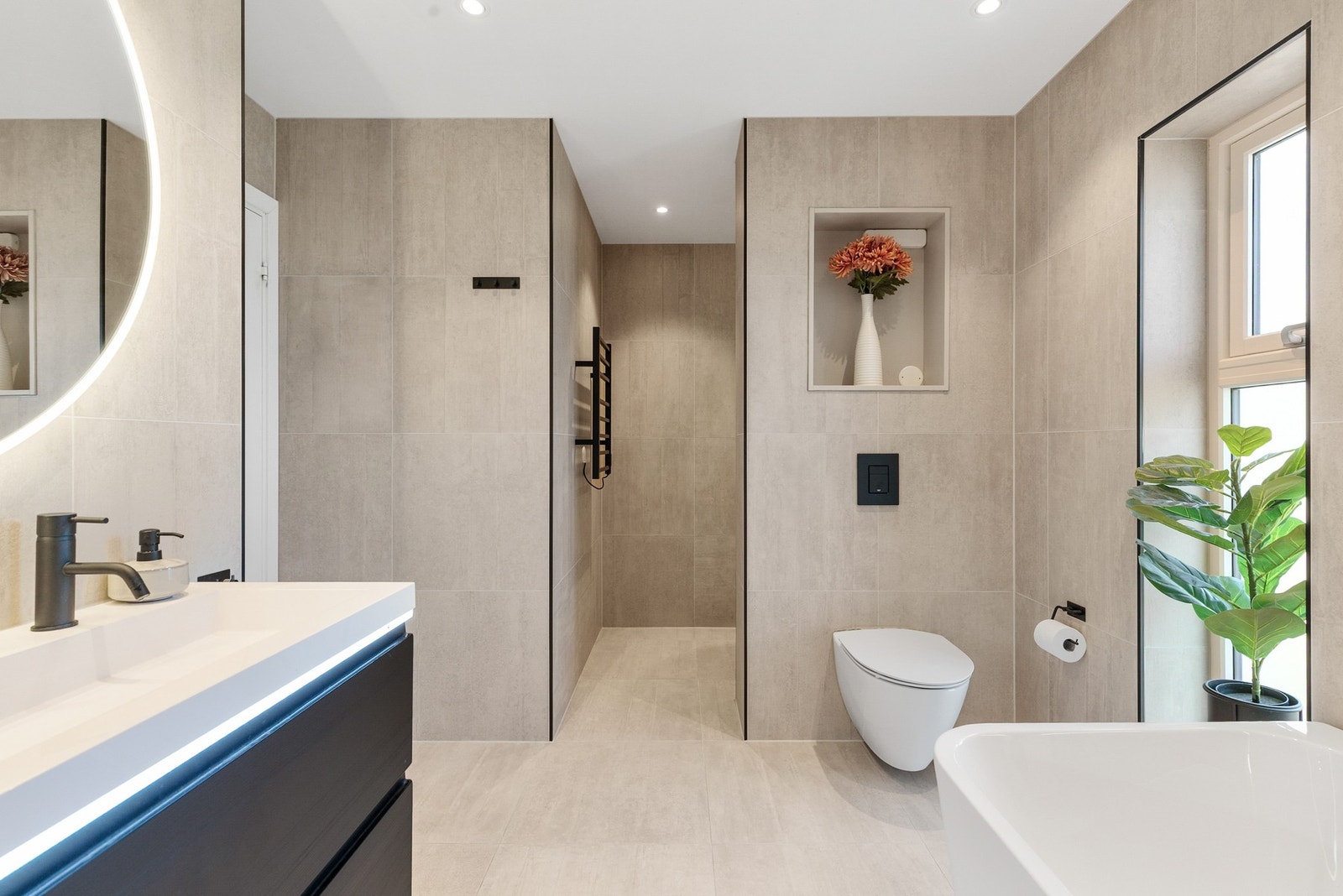 Videre er badet innredet med dusjnisje, badekar og vegghengt toalett Galleribilde