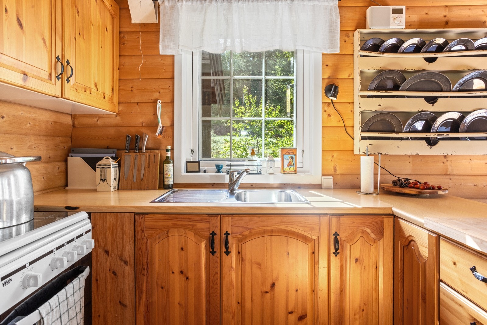 Kjøkkenet har skap og benkplass - innredning med profilerte fronter. Gasskomfyr og ned felt oppvaskum. Galleribilde