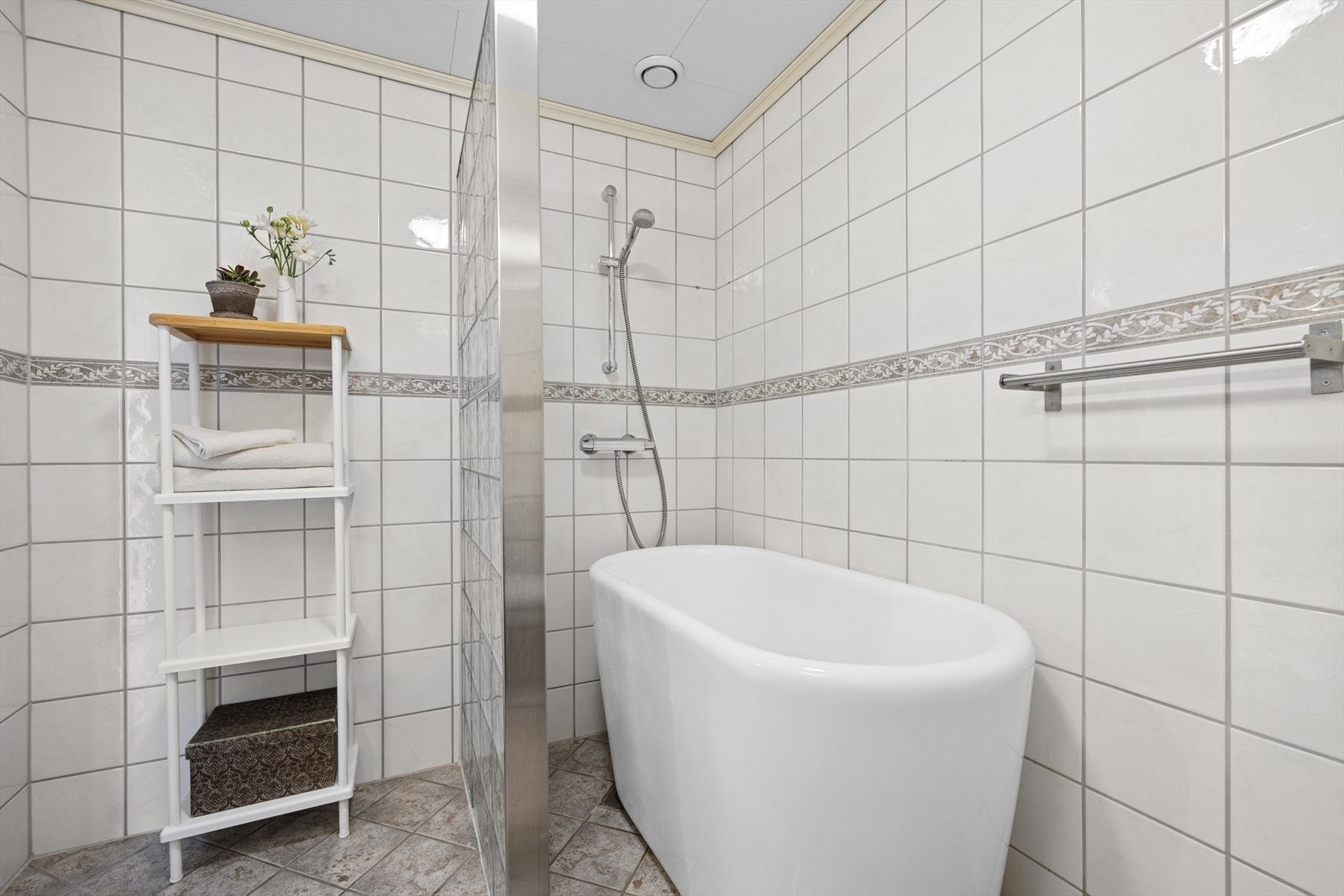 Badekar med dusj bak halvvegg av glassbyggerstein. Galleribilde