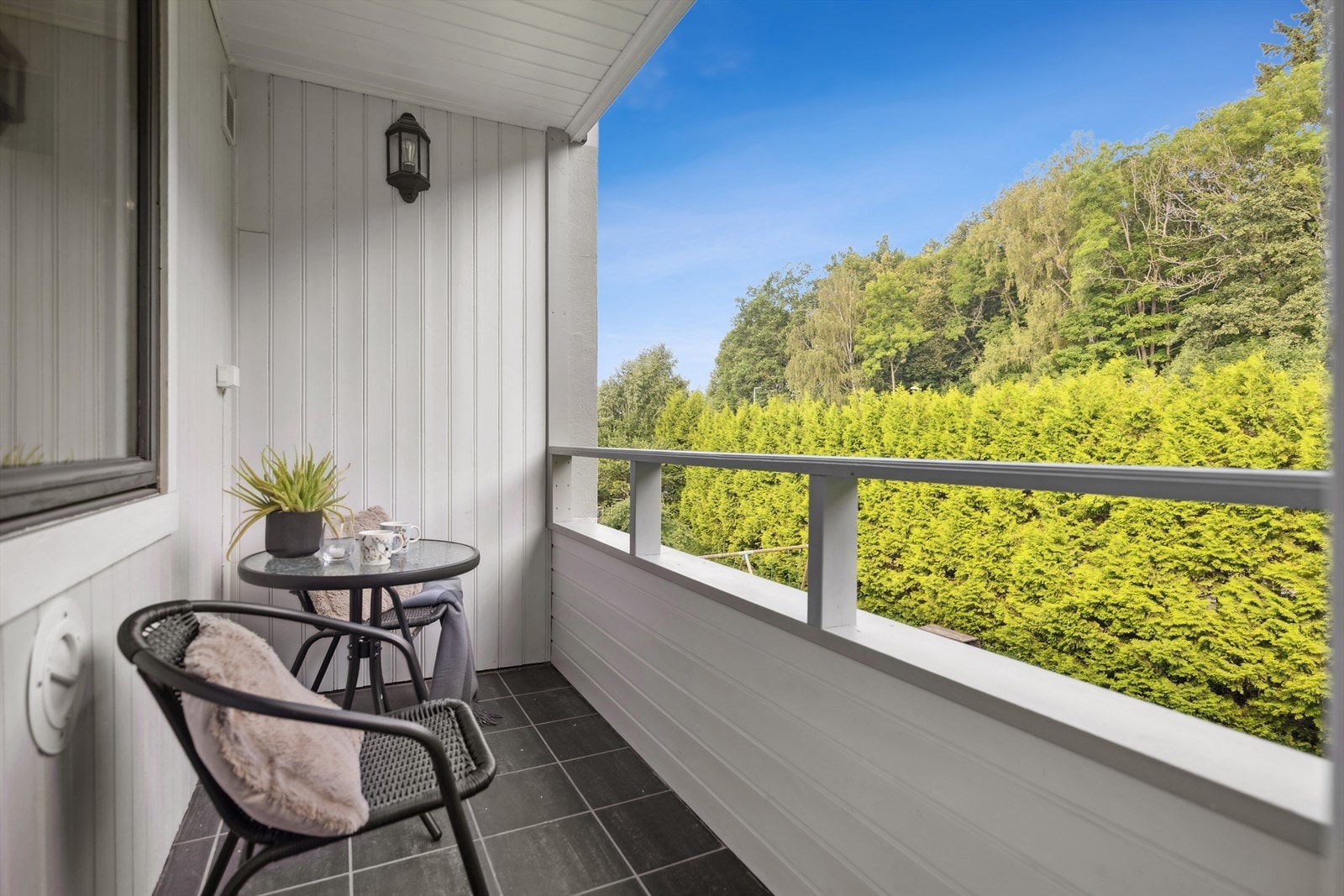 Balkongen er vendt ut mot sameiets hageareal med plen, beplantninger og lekeplass til ungene. Galleribilde