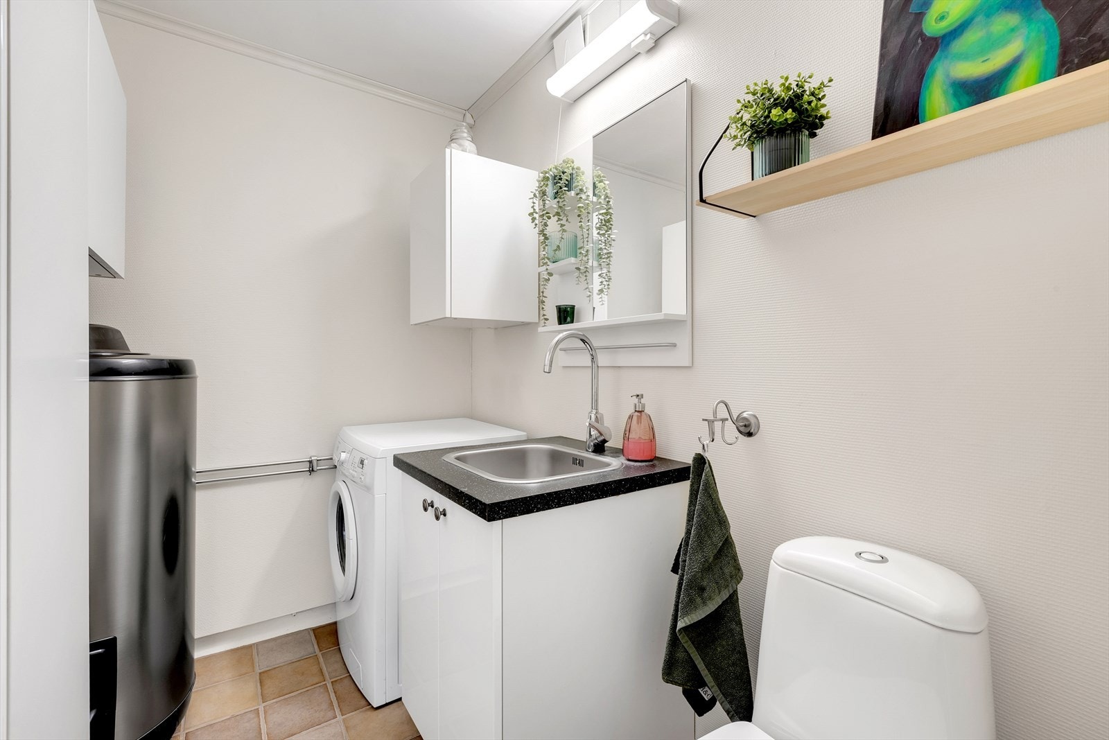 Praktisk vaskerom med toalett, servant og opplegg for vaskemaskin. Galleribilde