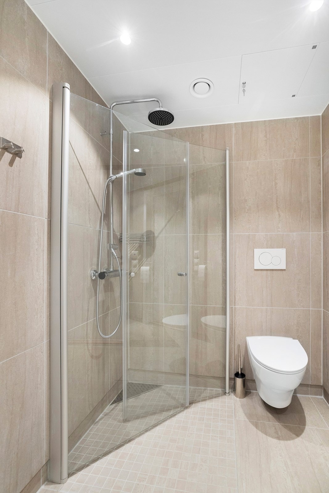 Badene er utstyrt med servant over innredning, overliggende speil med belysning, toalett og dusjhjørne med innfellbare vegger Galleribilde