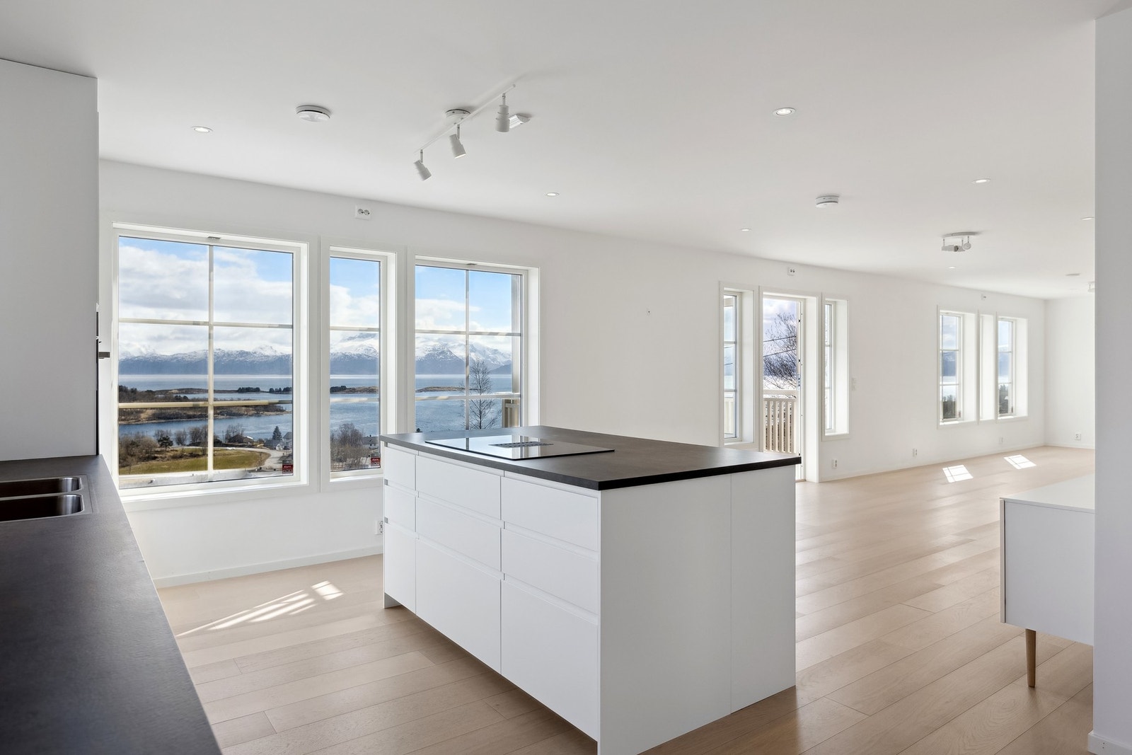 Kjøkkenet er boligens hjerte - med åpen løsning mot stue og store vindusflater Galleribilde