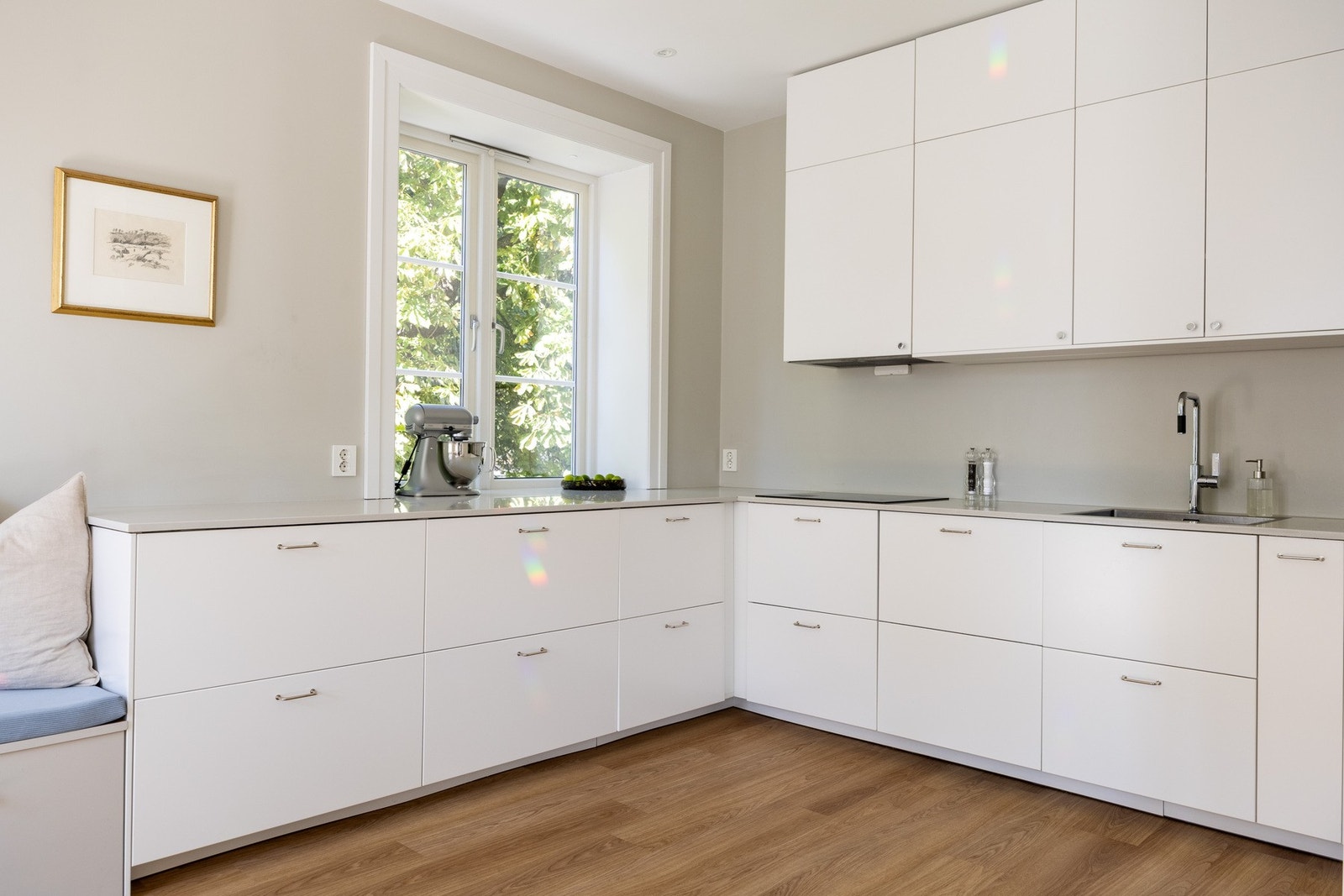 Stilrent Ikea kjøkken fra 2022 med glatte lyse fronter og benkeplate av stein. Galleribilde