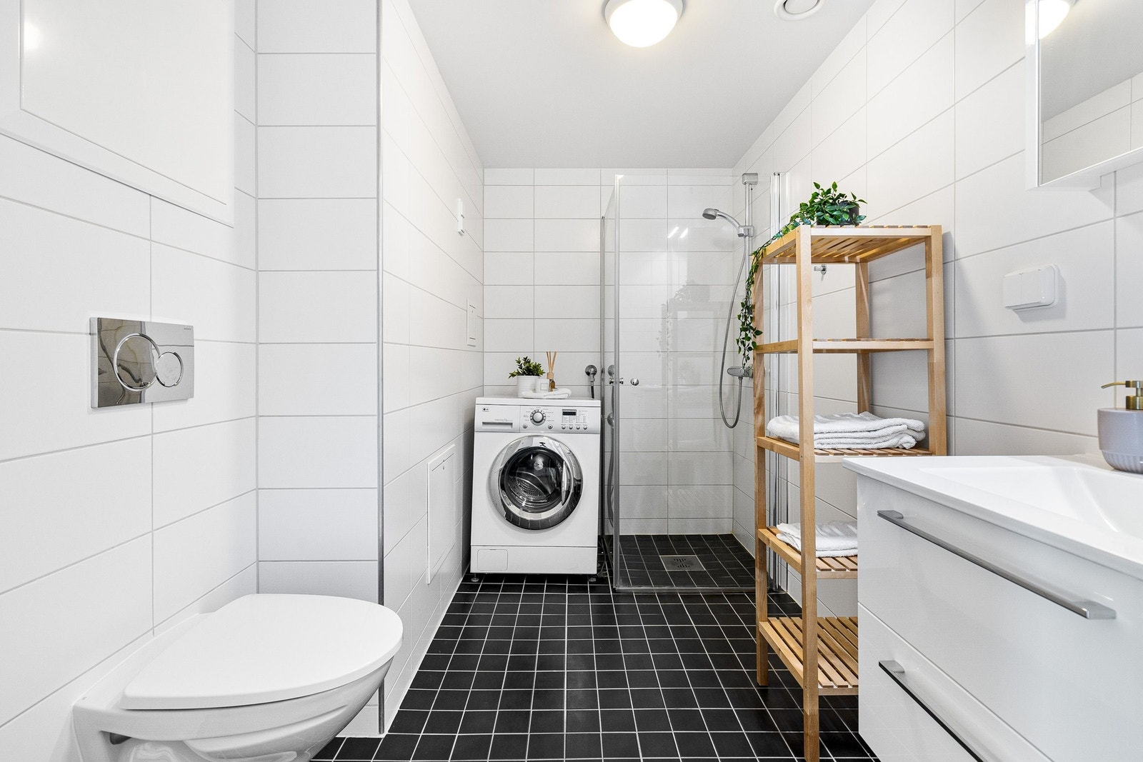 Bad med flislagt gulv og vegger, veggmontert klosett, opplegg vaskemaskin og deilig dusjhjørne. Galleribilde