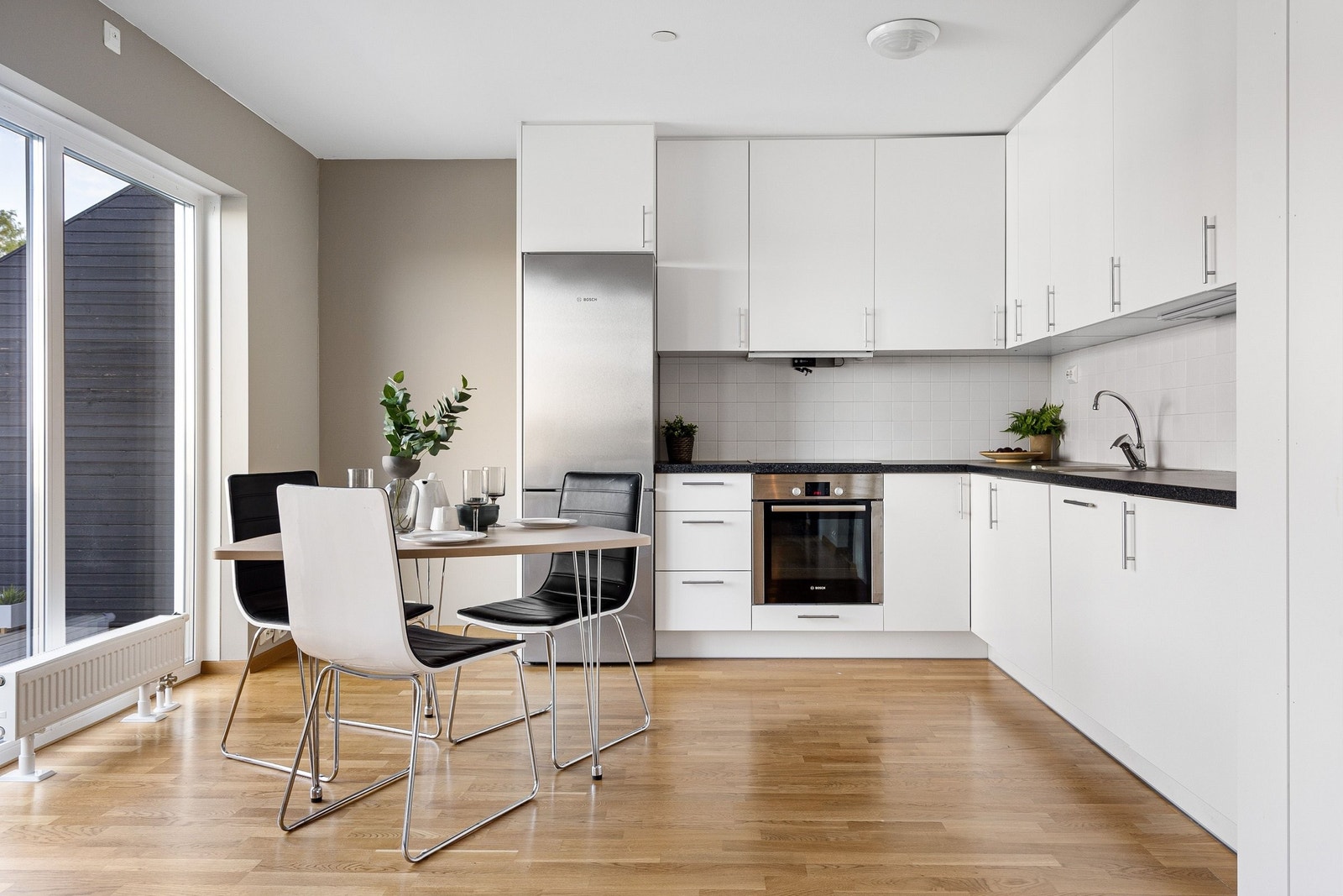 Lyst kjøkken med store vinduer fra gulv og nesten helt opp til taket. Flislagt mellom benk og overskap. Godt med skap-plass, flotte hvitevarer medfølger inkl oppvaskmaskin. Meget praktisk og god plass til spisestue/sittegruppe. Galleribilde