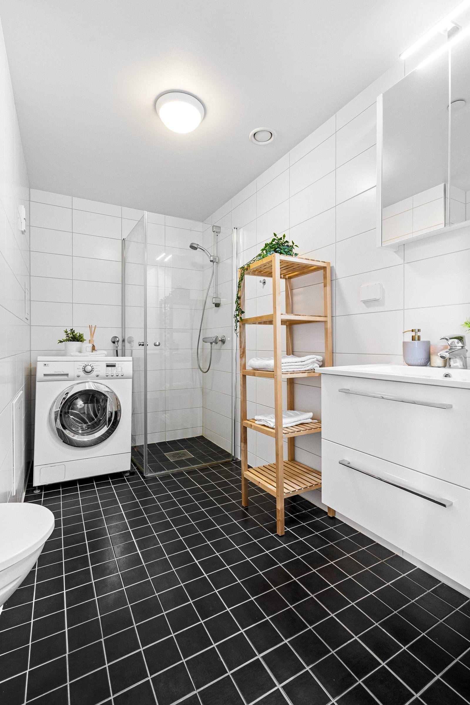 Bad med flislagt gulv og vegger, veggmontert klosett, opplegg vaskemaskin og deilig dusjhjørne. Galleribilde