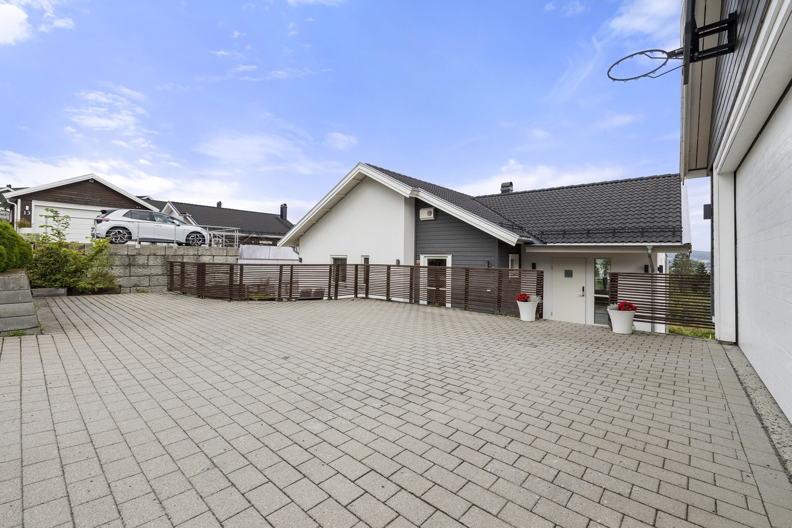 Stor, steinbelagt gårdsplass med parkeringsmuligheter og adkomst til garasje. Galleribilde