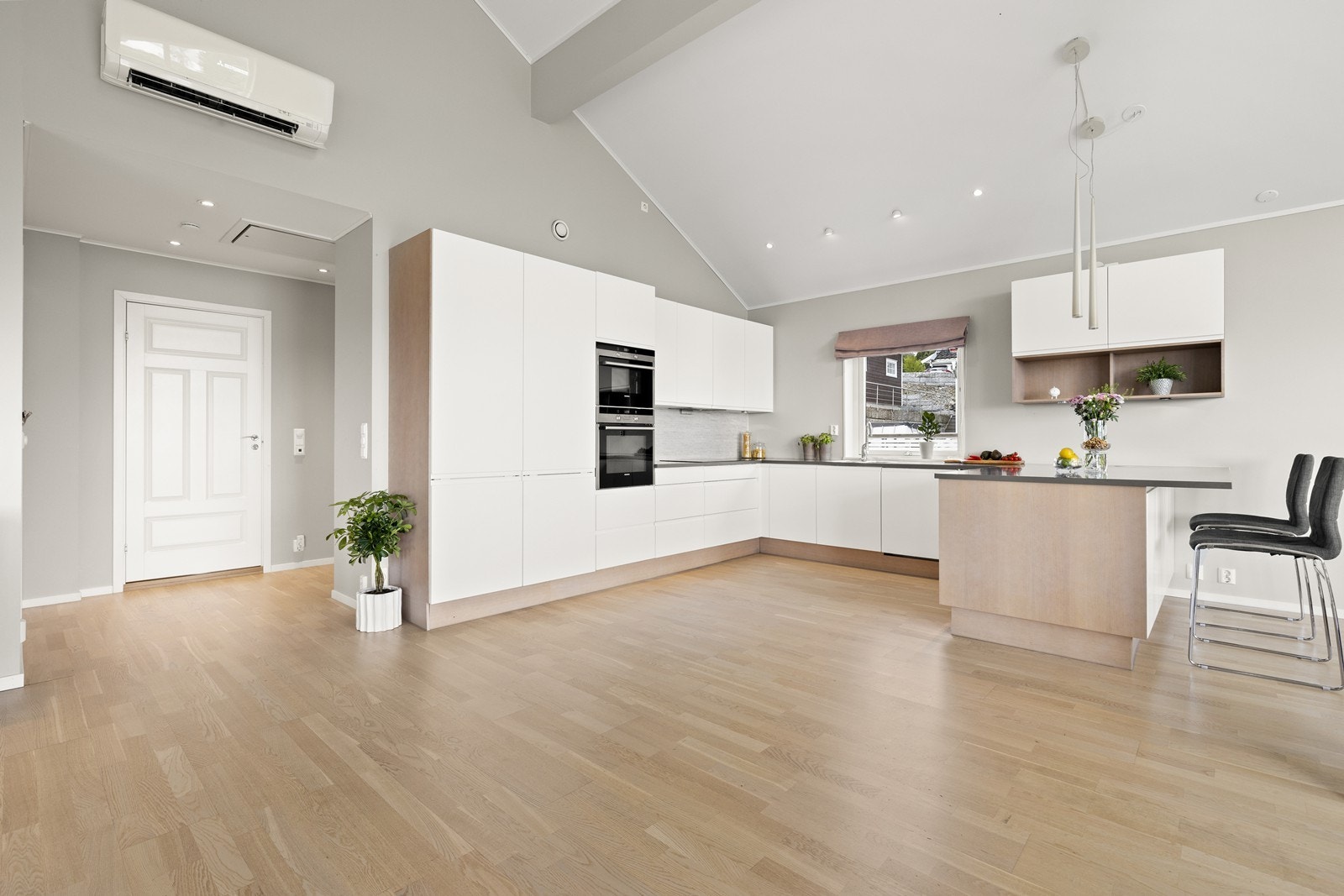 Innredningen framstår minimalistisk med hvite, slette fronter, gripetak og laminat benkeplate. Galleribilde