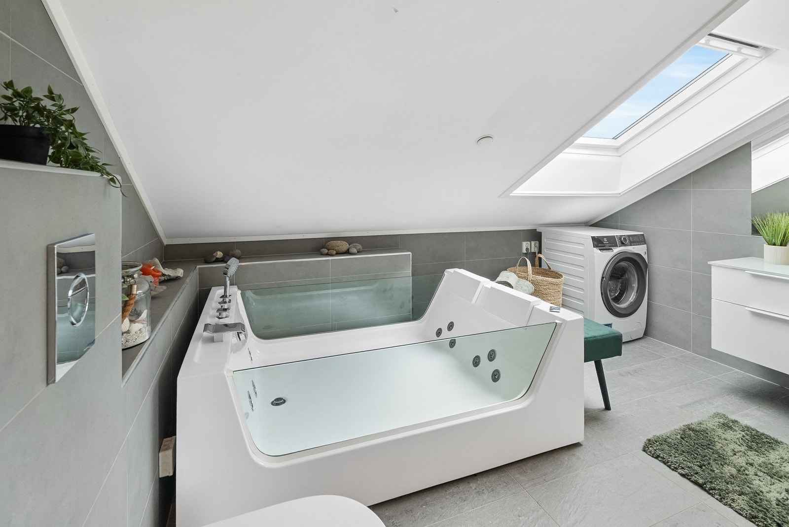 Badet er innredet med moderne innredning, boblebadekar, dusjvegg med dusjkar, veggmontert toalett og opplegg for vaskemaskin. Galleribilde