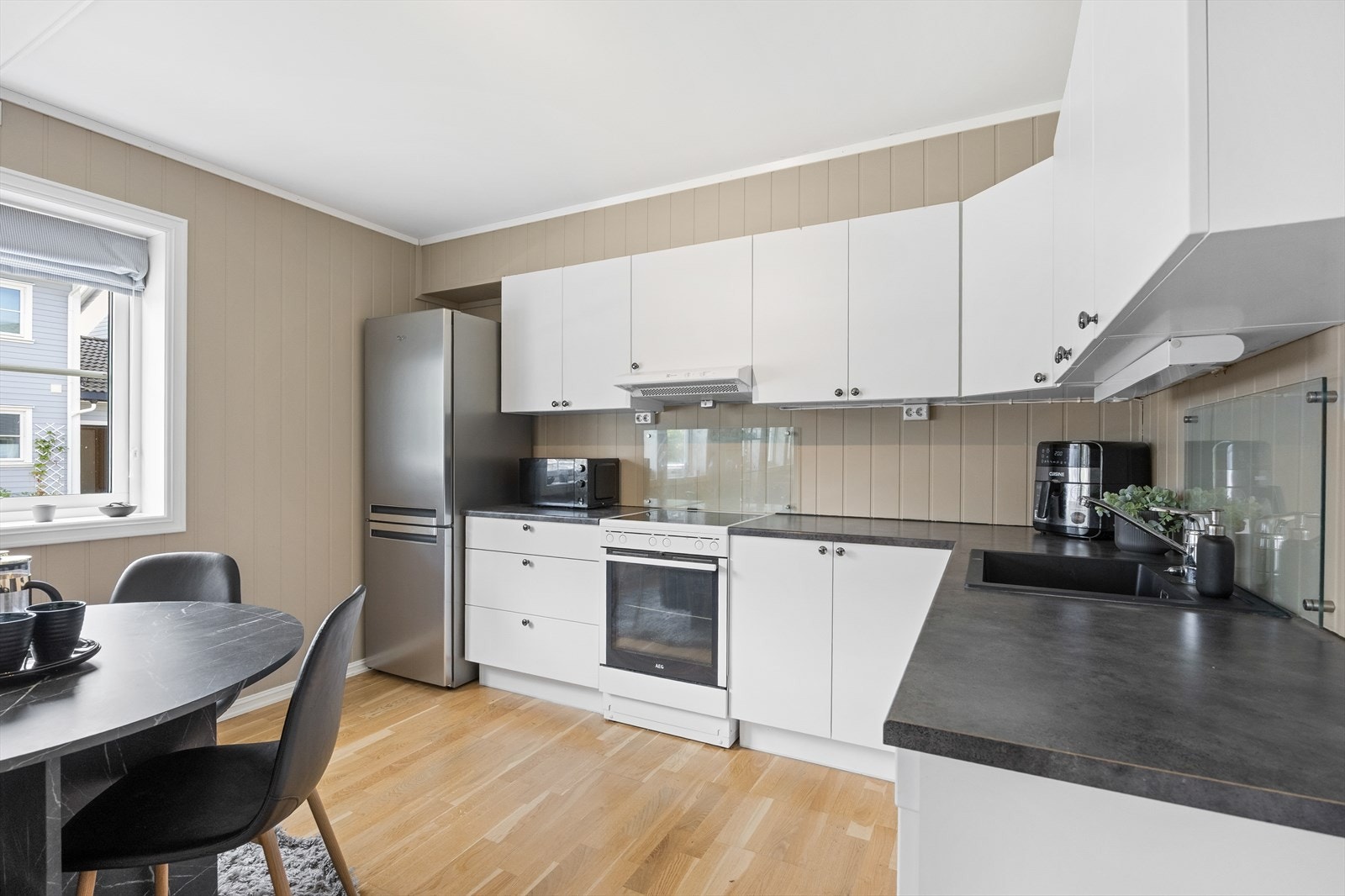 Innredningen er klassisk med hvite, slette fronter, laminat benkeplate og belysning under overskap. Galleribilde