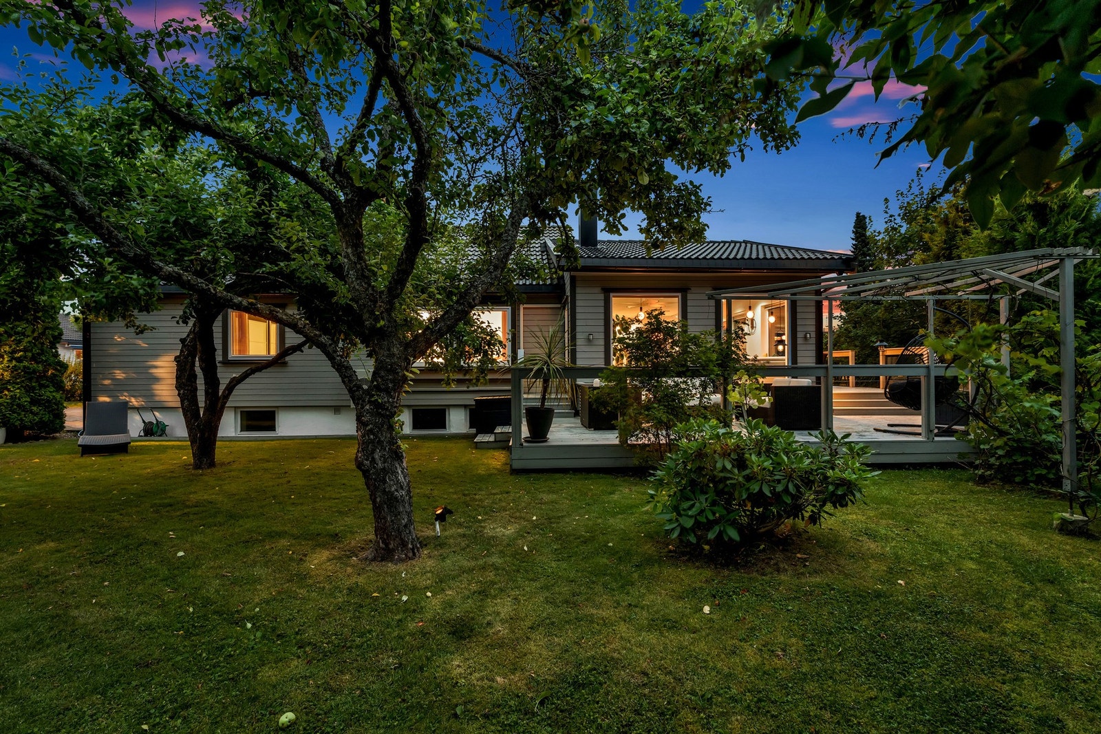 En flott skjermet hage med gressplen og beplantning Galleribilde