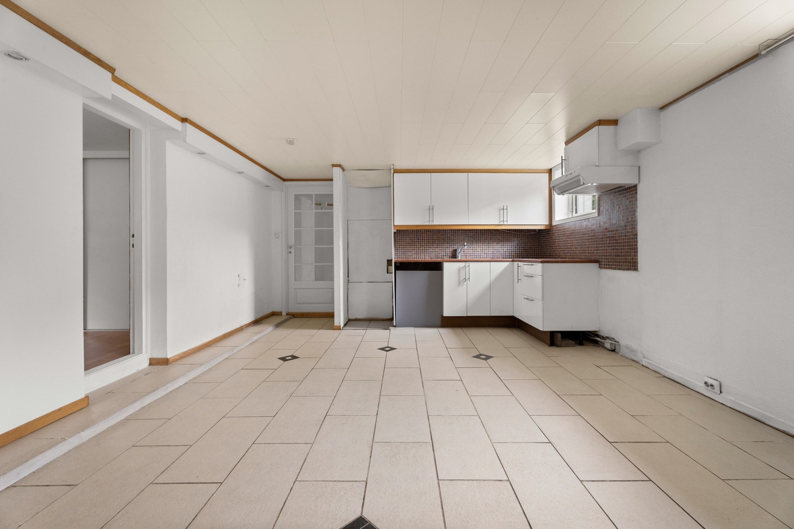 Vegger har malt murpuss og fliser over benk. Taket er kledd med MDF-panel, og gulvet er flislagt. Kjøkkenet er utstyrt med over- og underskap, laminert benkeplate med nedfelt vask, samt opplegg og plass til frittstående hvitevarer Galleribilde