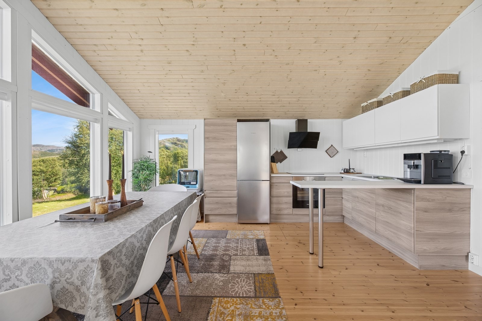 Kjøkkenet er innredet med moderne, glatte fronter i trefarget finish som gir et varmt og naturlig uttrykk. Galleribilde