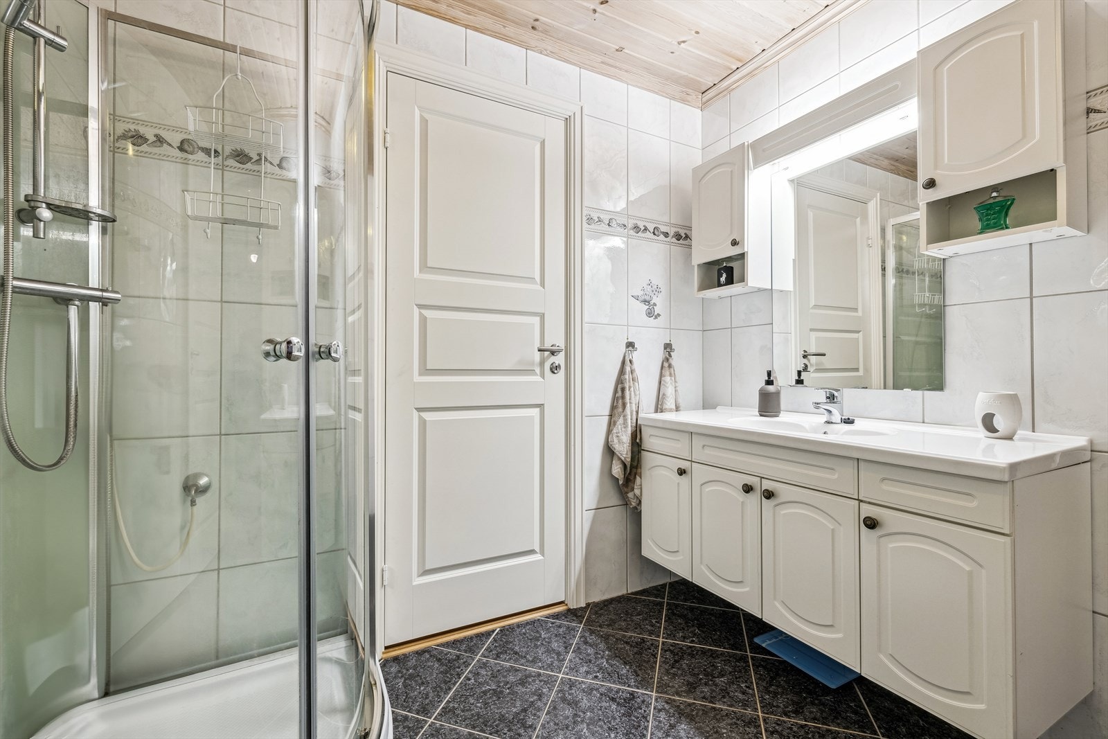 Flislagt bad med innredning bestående av dusjkabinett, baderomsinnredning og varmekabler i gulv. Galleribilde