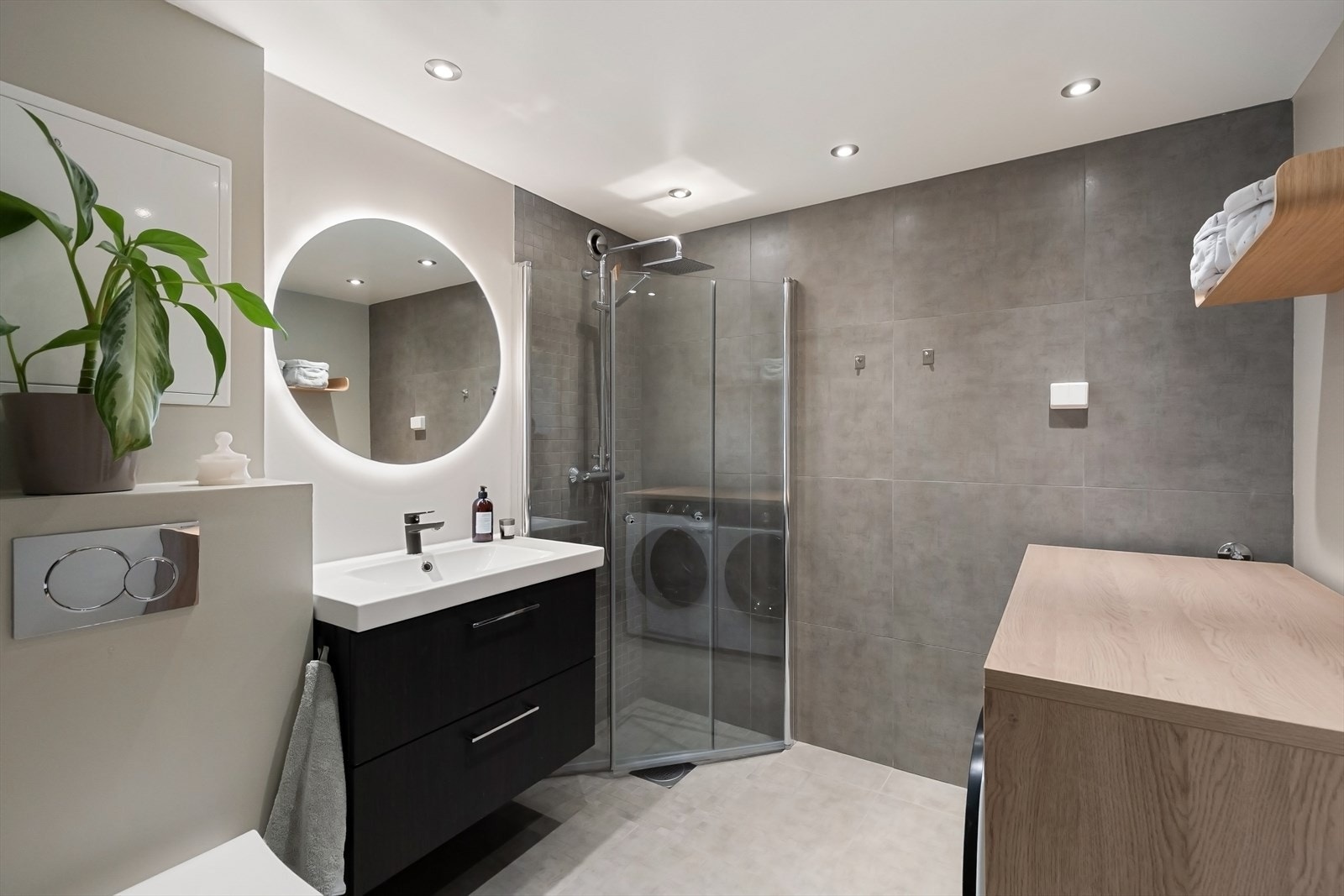 Moderne bad med dusjhjørne, servant med skuffer, speil og wc. Galleribilde