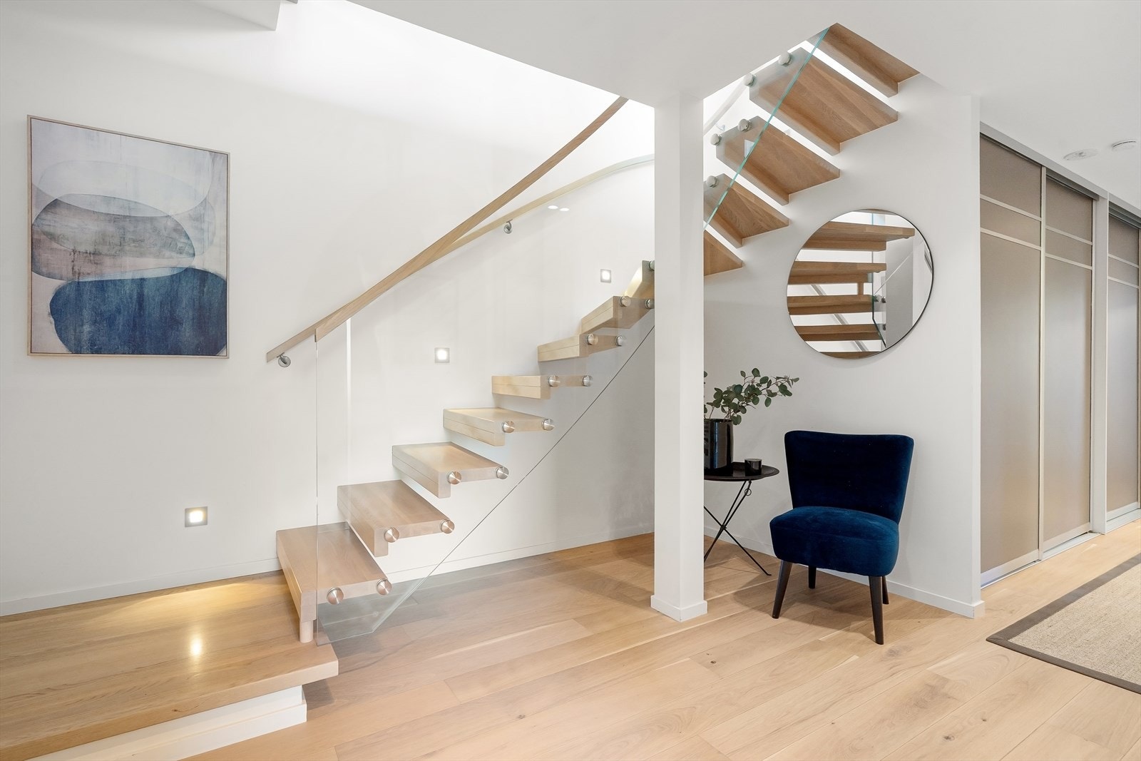 Innvendige trapper med trinn belagt med samme parkett som gulv. Rekkverk i glass og håndløpere på begge sider Galleribilde