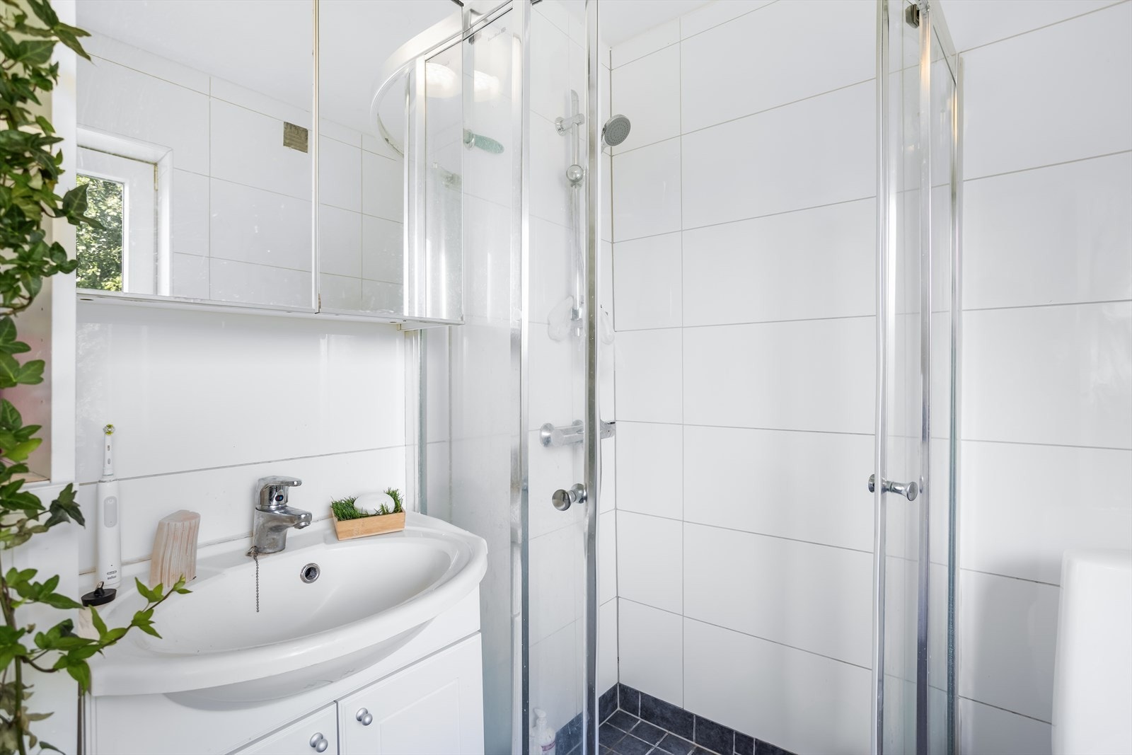 Badet er innredet med servantskap, speilskap, dusj med skyvedører og opplegg for vaskemaskin. Galleribilde