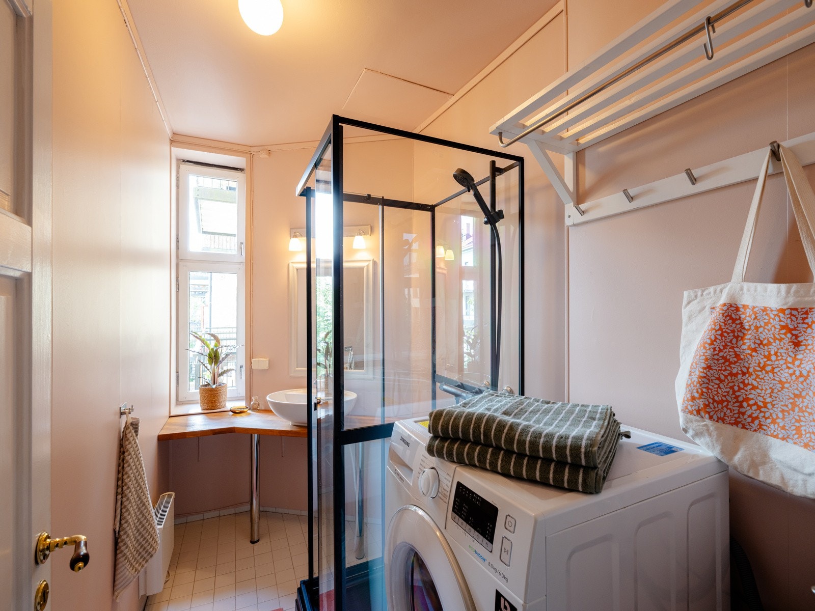 Baderommet har benkeplate med servantbolle, speil og belysning på vegg, dusjkabinett (2025) og opplegg for vaskemaskin. Galleribilde