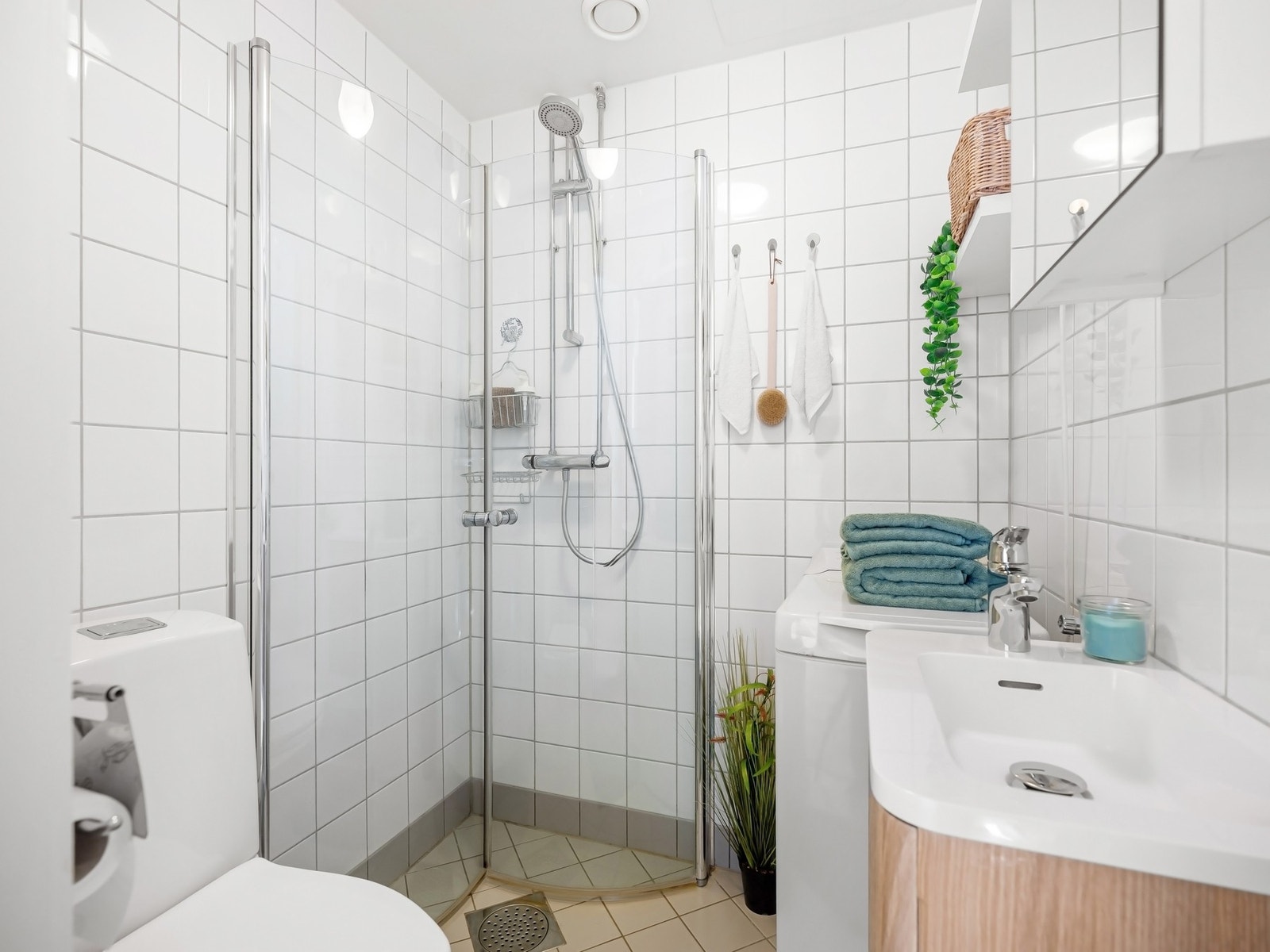 Badet er innredet med dusjhjørne, gulvmontert toalett, servant med blandebatteri og overskap. Galleribilde