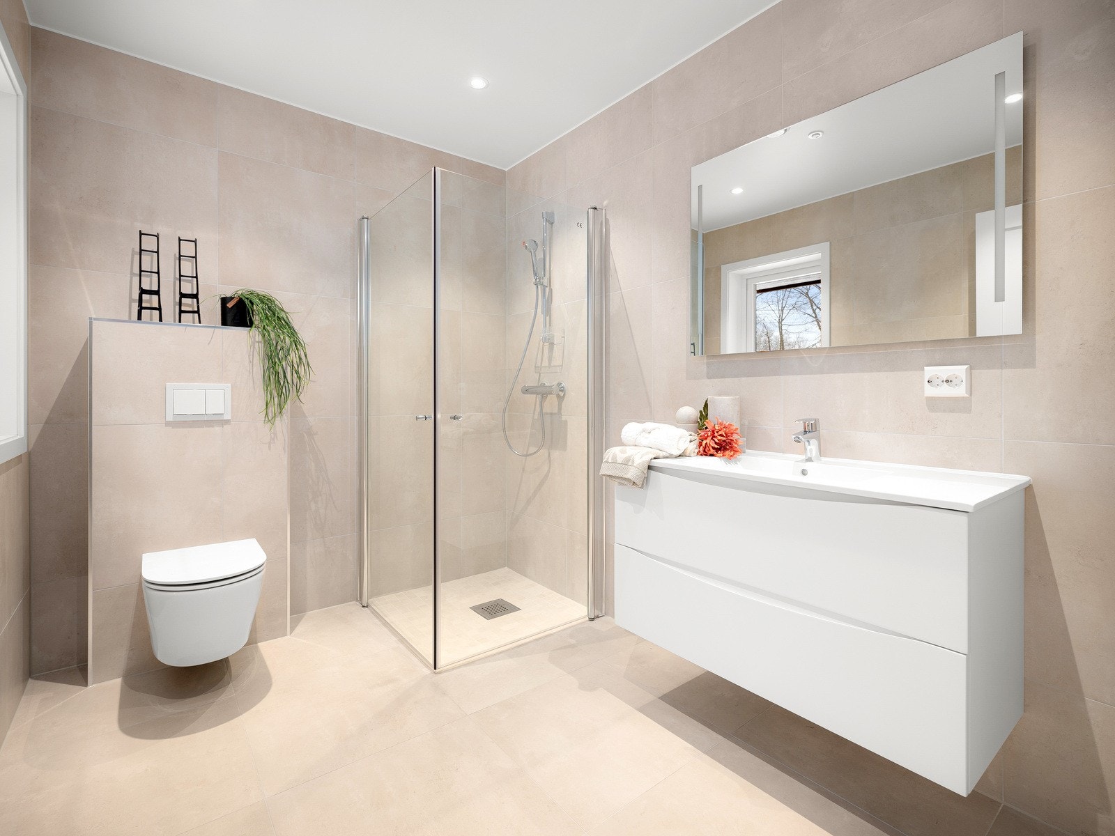 Badet er utstyrt med vegghengt toalett, dusjplass med svingbare glassdører, lekkert romslig baderomsmøbel og speil med lys Galleribilde