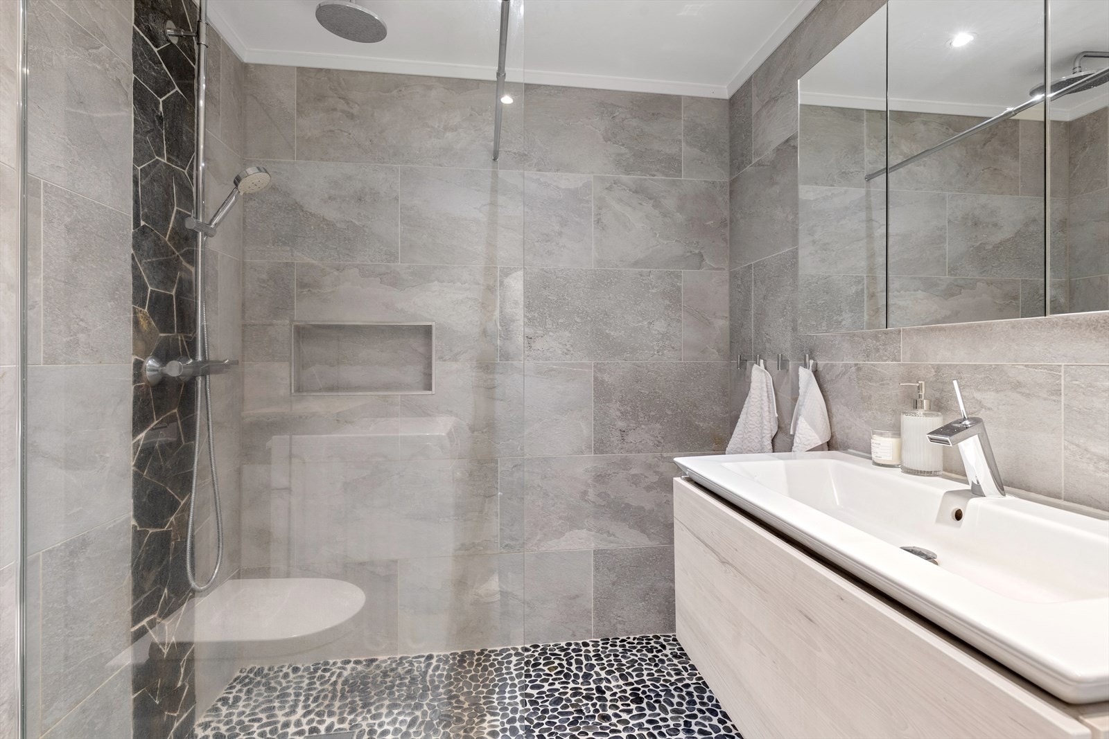 Lekker regnfallsdusj samt nisje i vegg for hårpleieprodukter - legg merke til naturstensmosaikkgulvet Galleribilde