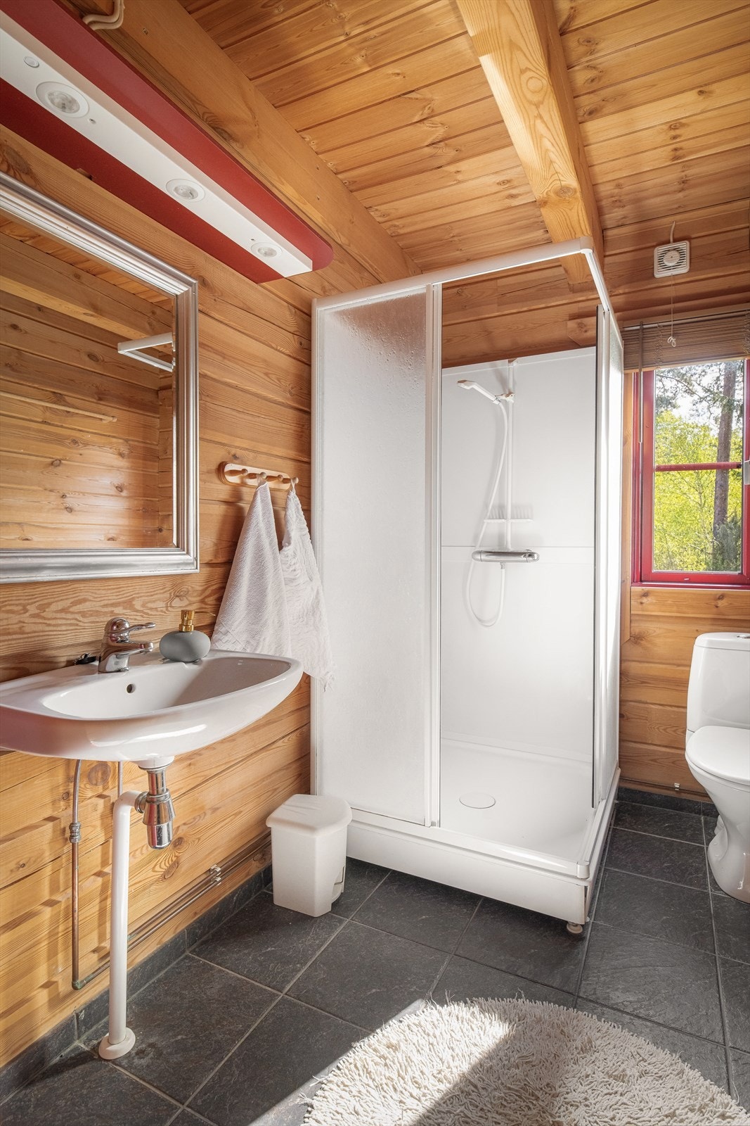 Badet er innredet med veggmontert servant, dusjkabinett og toalett. Galleribilde